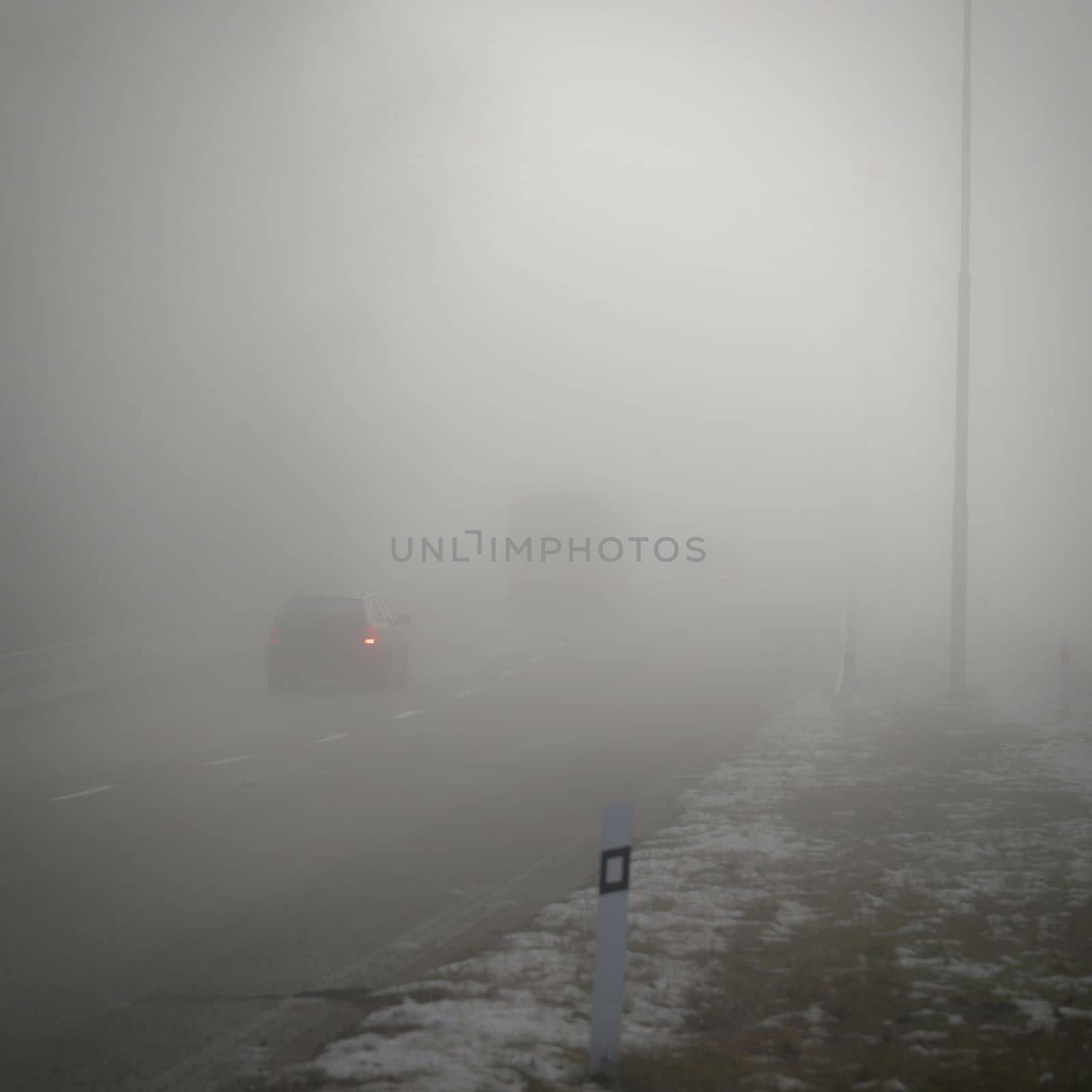 Cars in the fog. Traffic on the road in winter in bad weather. Dangers of driving cars. by Montypeter