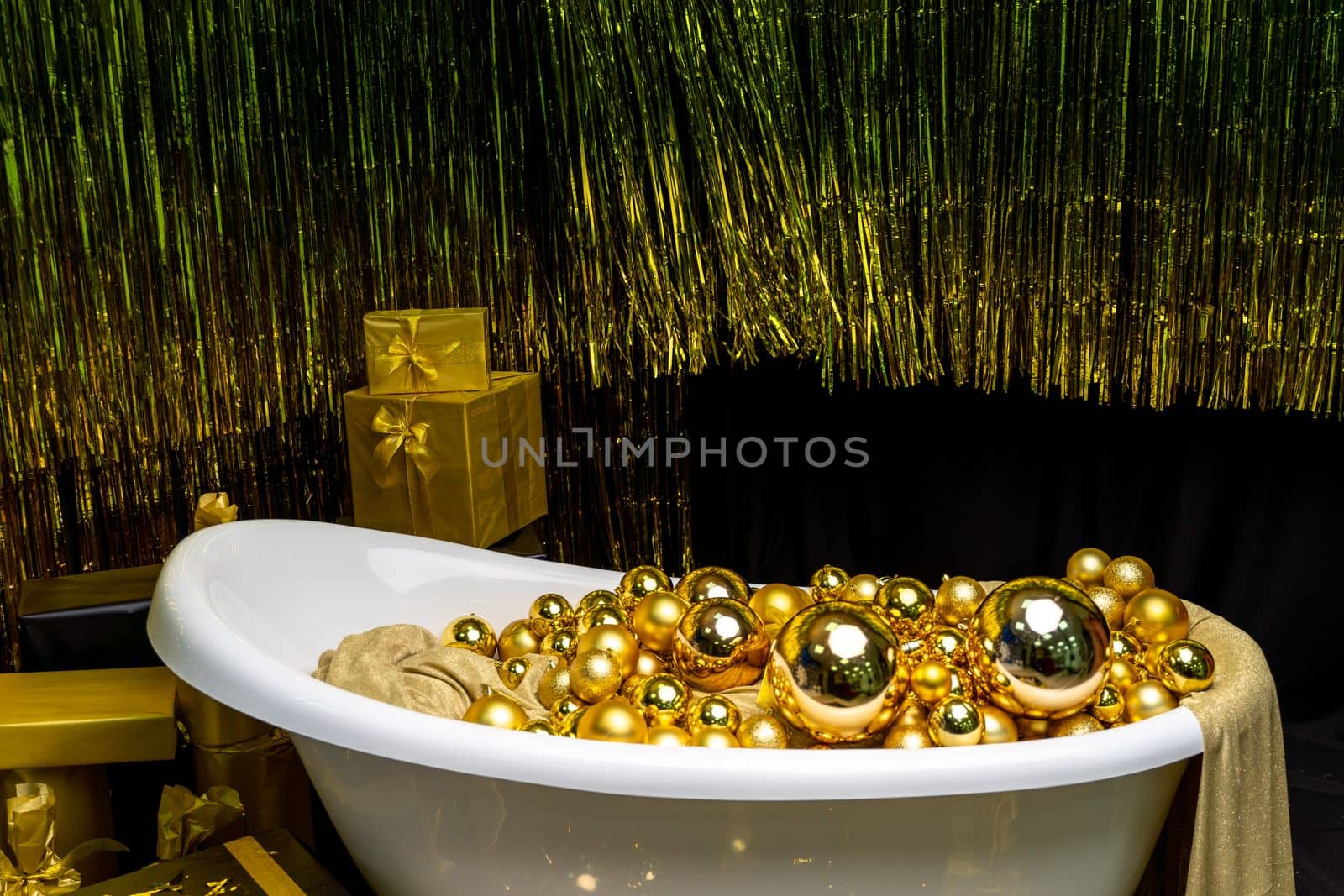 Bathtub full of golden balls. Vintage bright bathroom decorated with festive golden balls. New Year, Christmas bathroom interior
