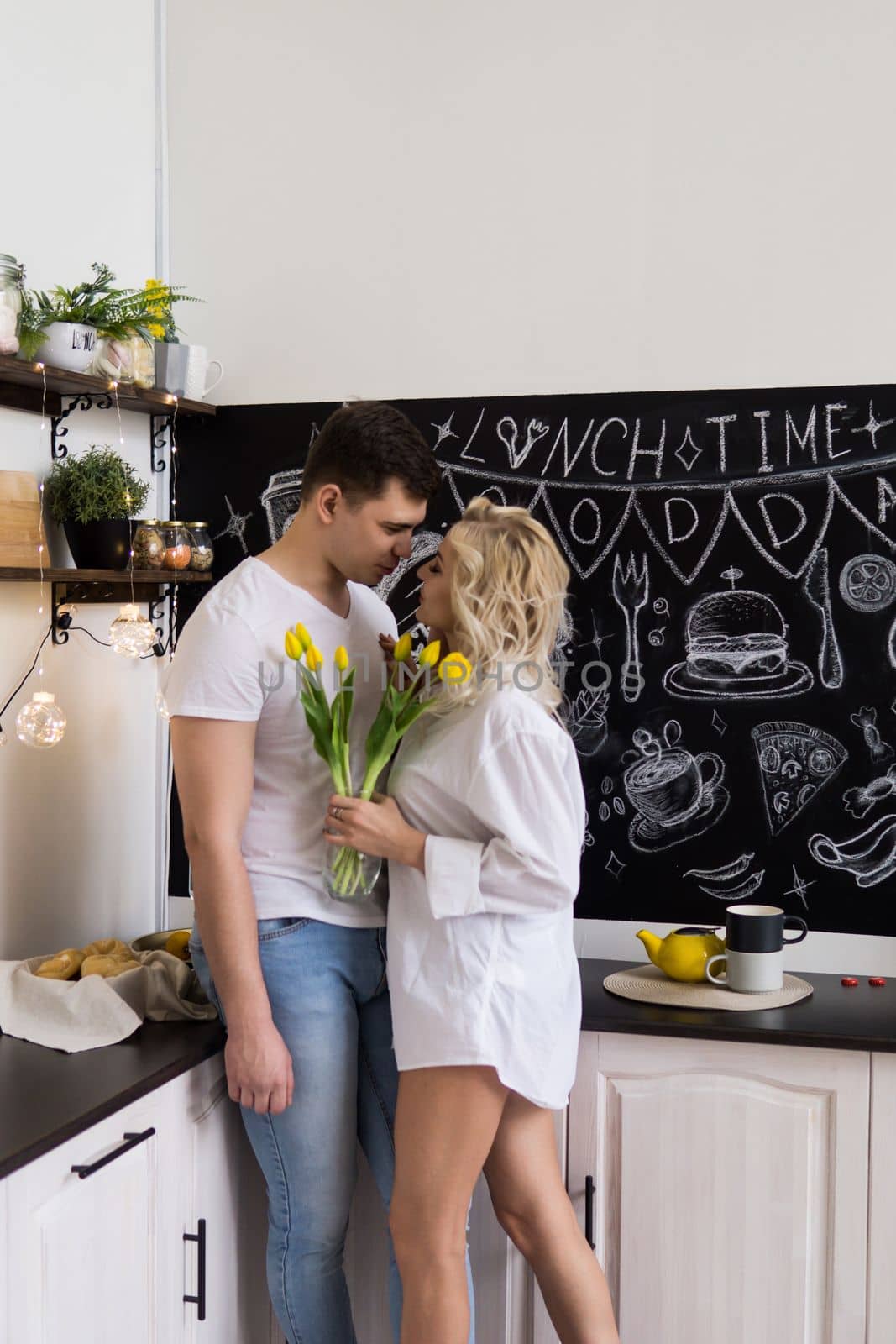 Love is quarantined during the Coronavirus. This is the new normal. A young couple in love in their home kitchen. by Annu1tochka