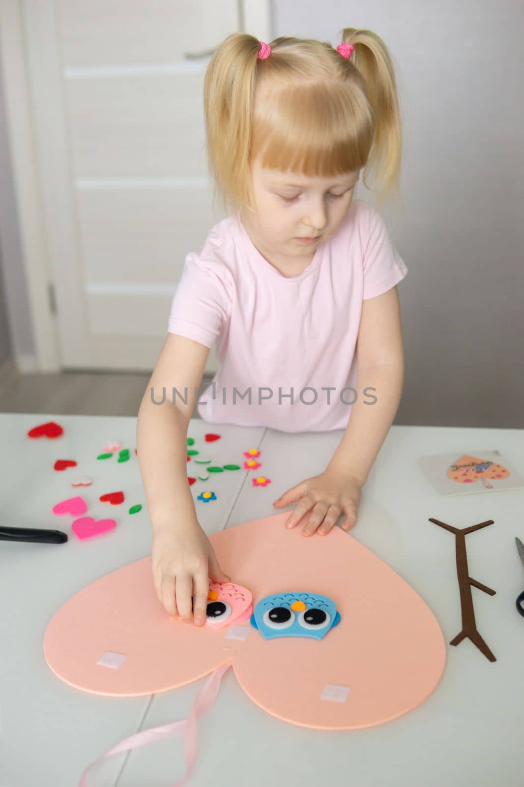 A blogger girl makes a felt craft for Valentine's Day in the shape of a heart. The concept of children's creativity and handmade