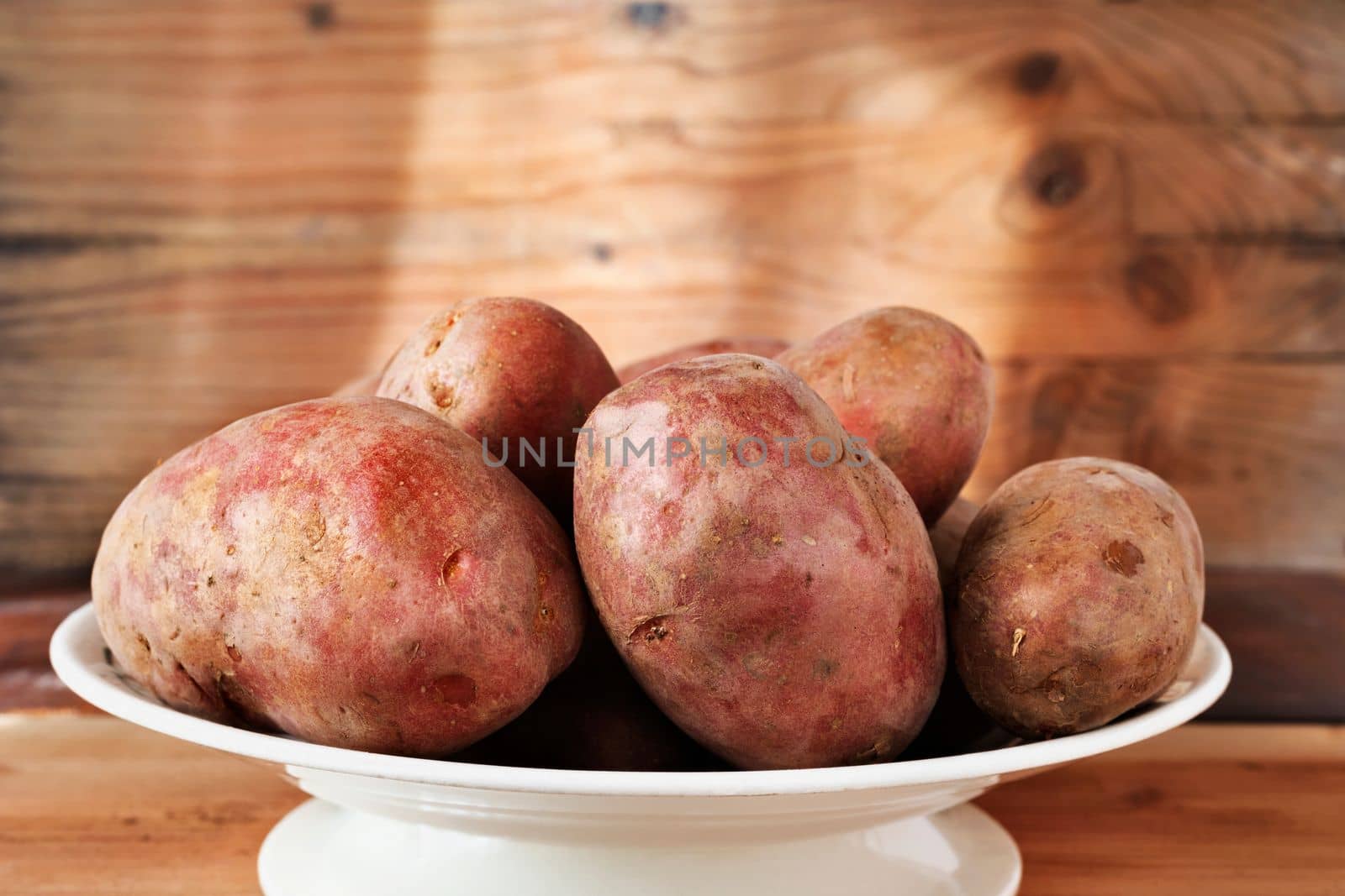Harvested uncooked potatoes on plate, agricultural occupation