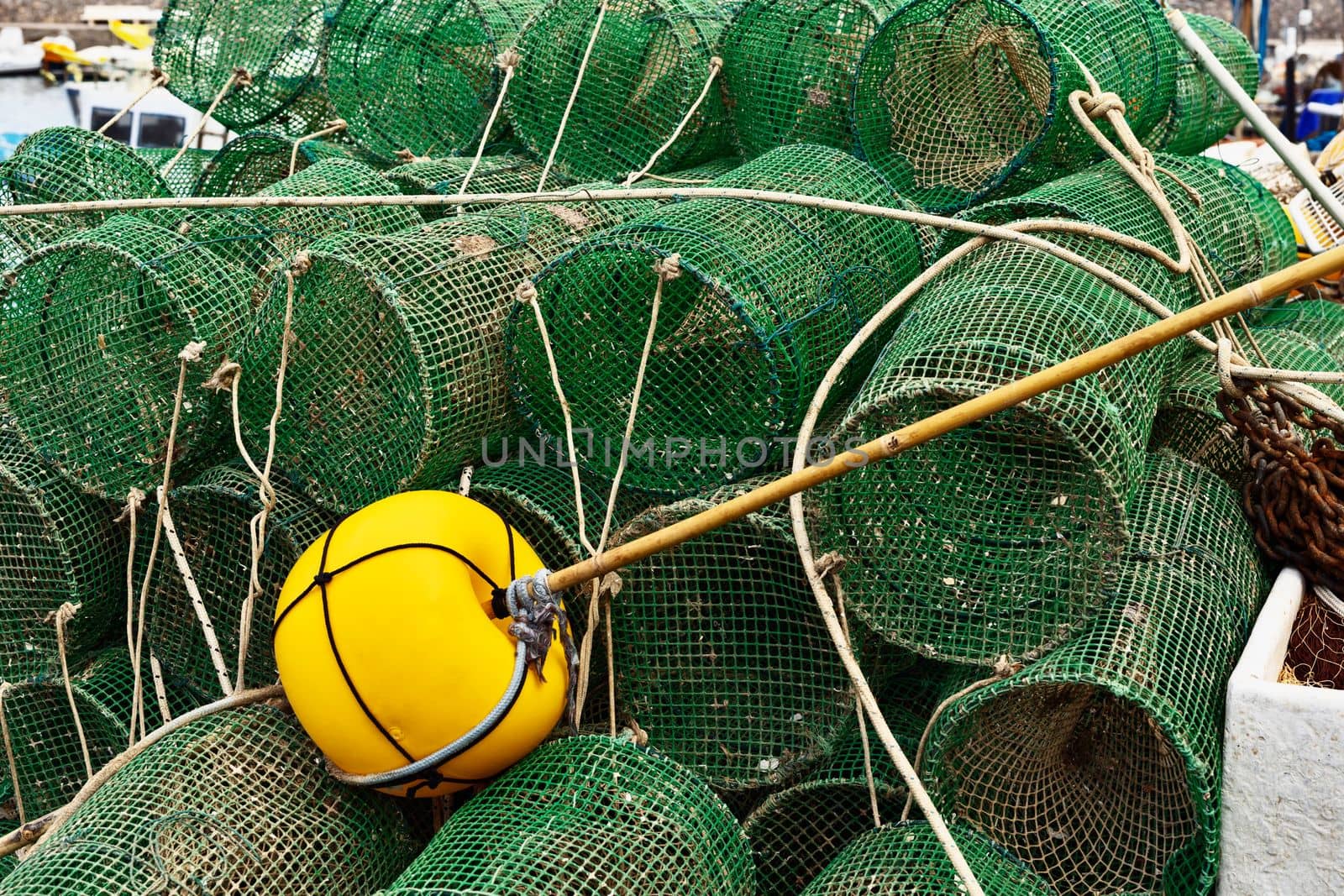 Stack of green fish traps and yellow float  at harbor
