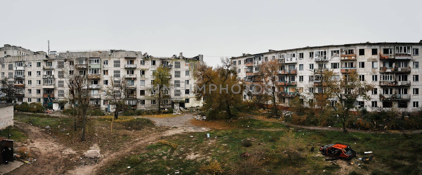Yard of destroyed apartment buildings in the war zone. Damage to a house as a result of artillery shelling. War in residential areas, broken windows and burned apartments. Armed conflict in Ukraine.
