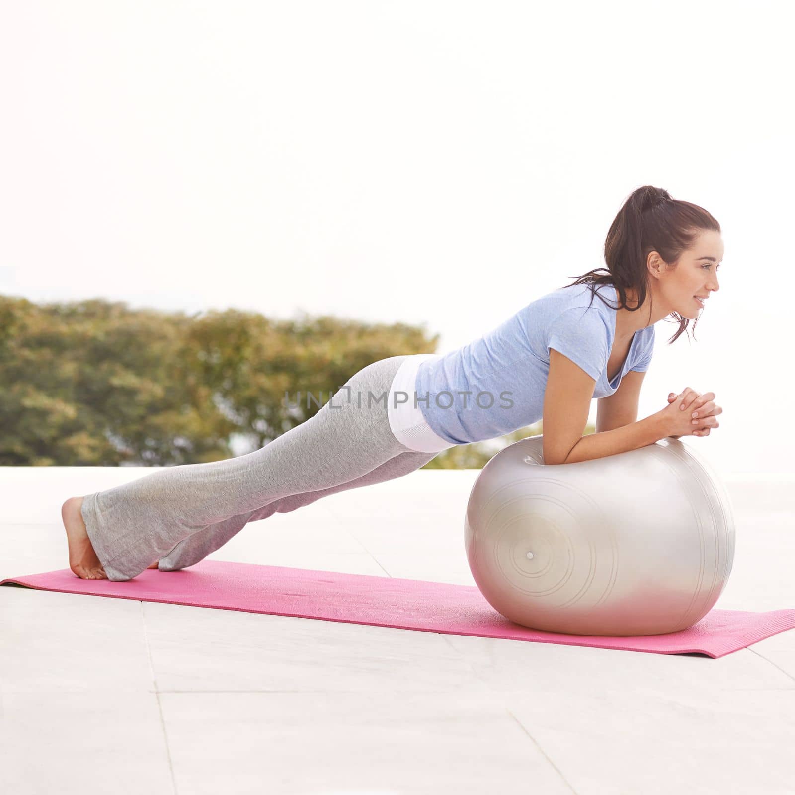 Lets get the ball rolling. Full length shot of a young woman doing yoga outdoors. by YuriArcurs