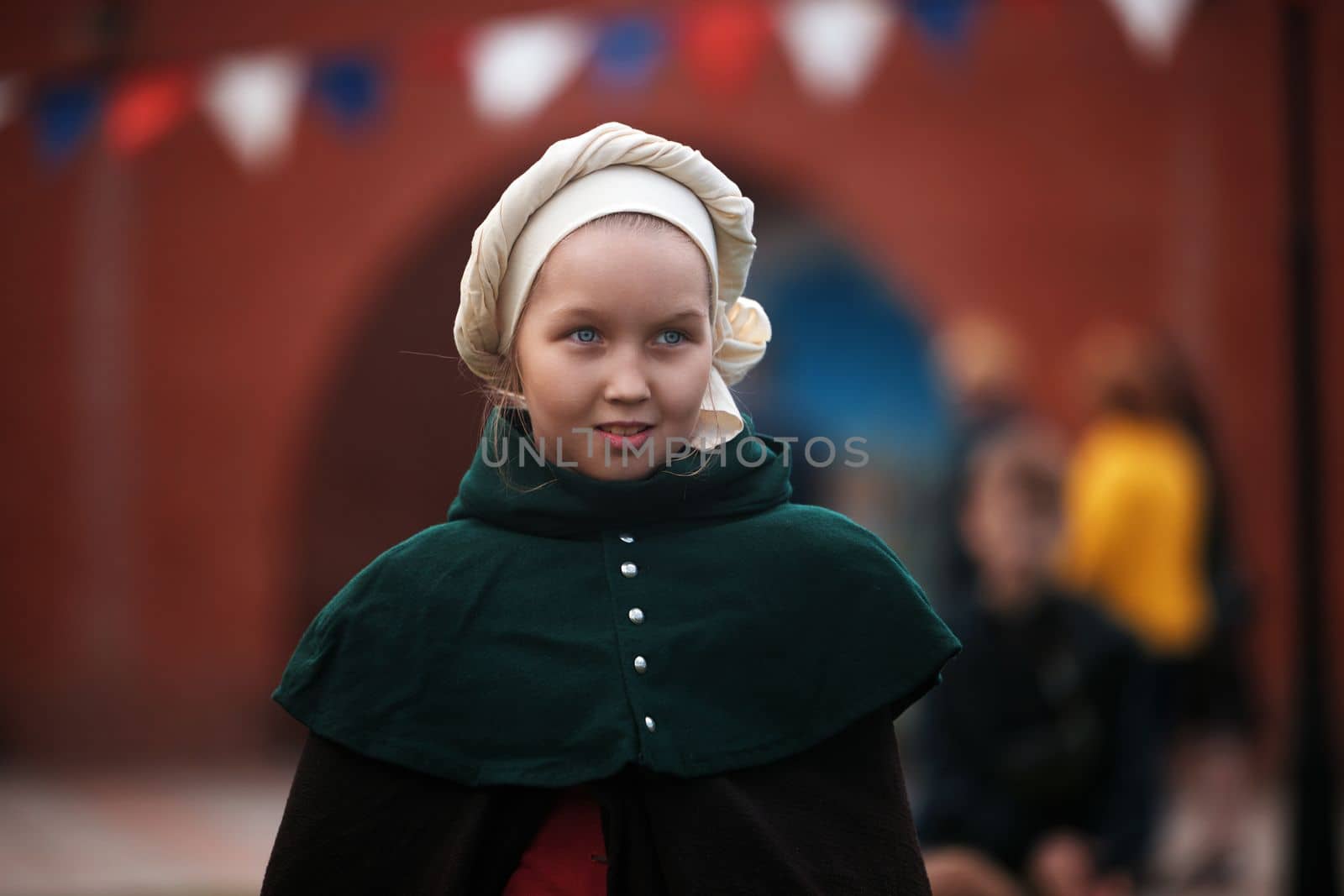 Portrait of a young girl in a medieval castle. A little girl in medieval dress walking through a yard. historical reconstruction. 14.05,2022. Yoshkar-Ola, Russia.