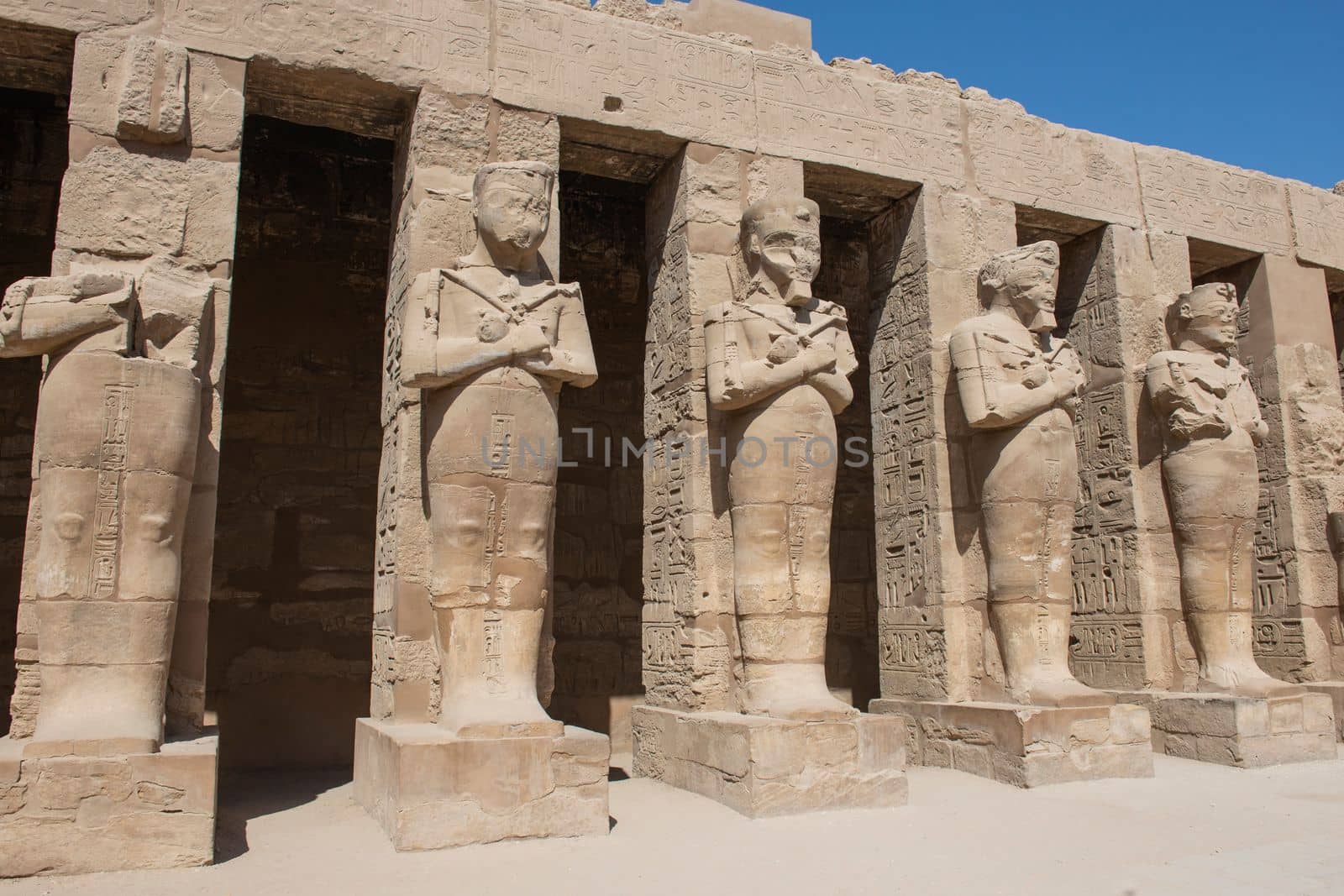 Large statues of Ramses III in ancient egyptian Karnak Temple with columns in courtyard area