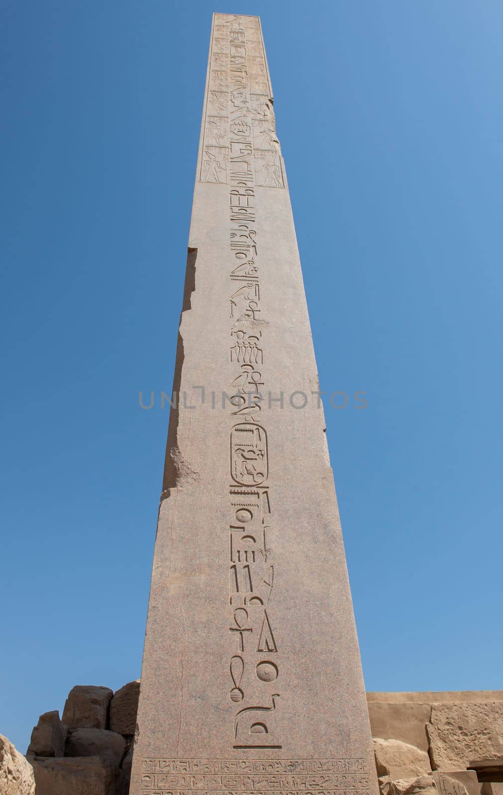 Hieroglypic carvings on tall obelisk column at the ancient egyptian Karnak Temple in Luxor Egypt against blue sky background