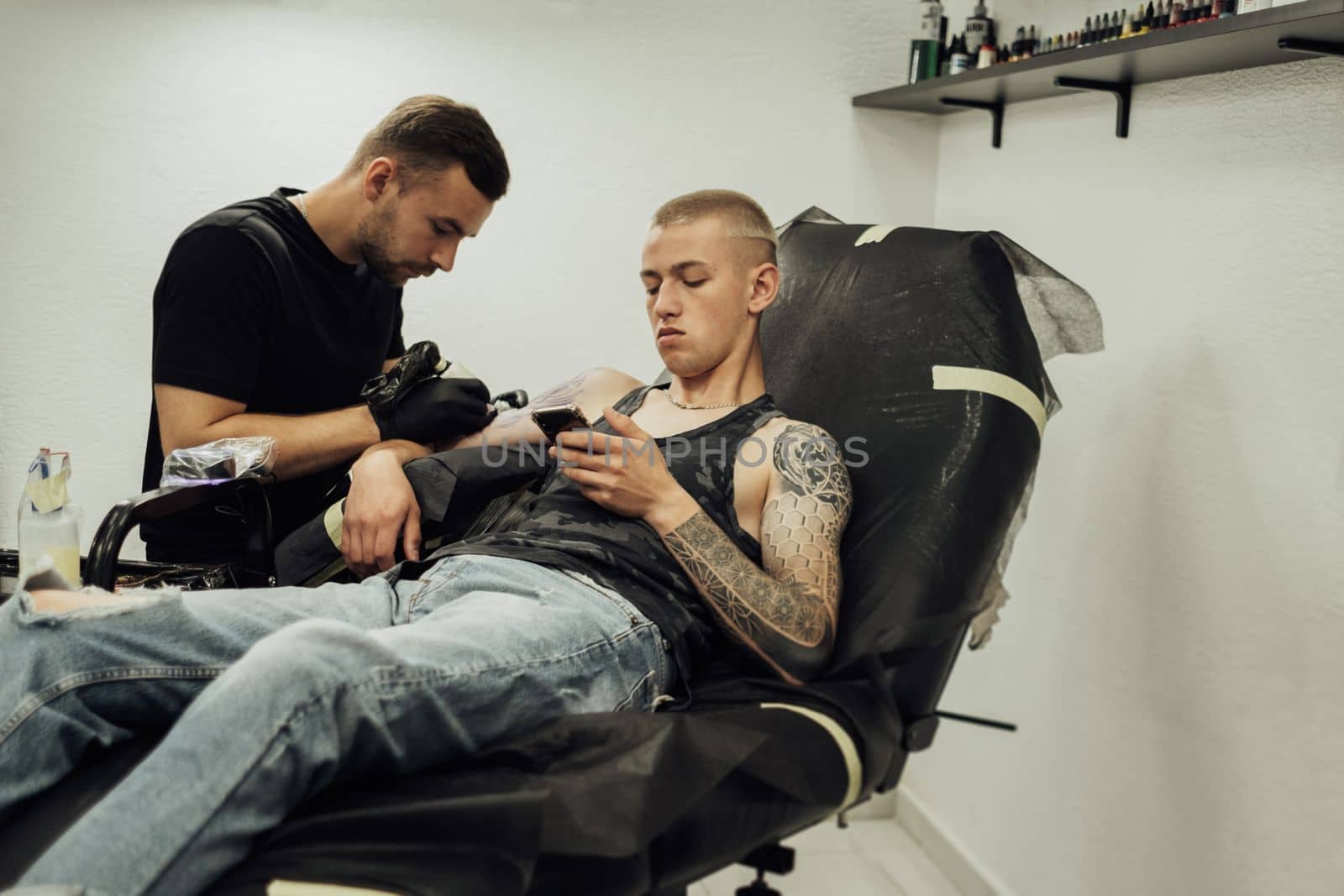 Tattooed Man on the Process of Creating New Tattoo at Studio, Male Artist Draws on the Client Skin by Romvy