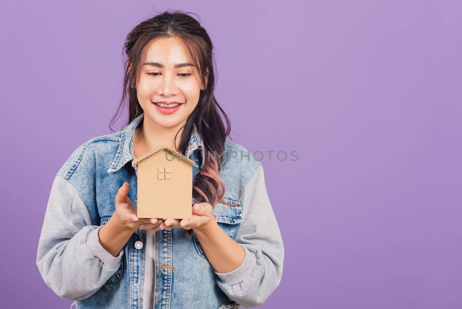 woman wear denim excited smiling holding house model on hand by Sorapop