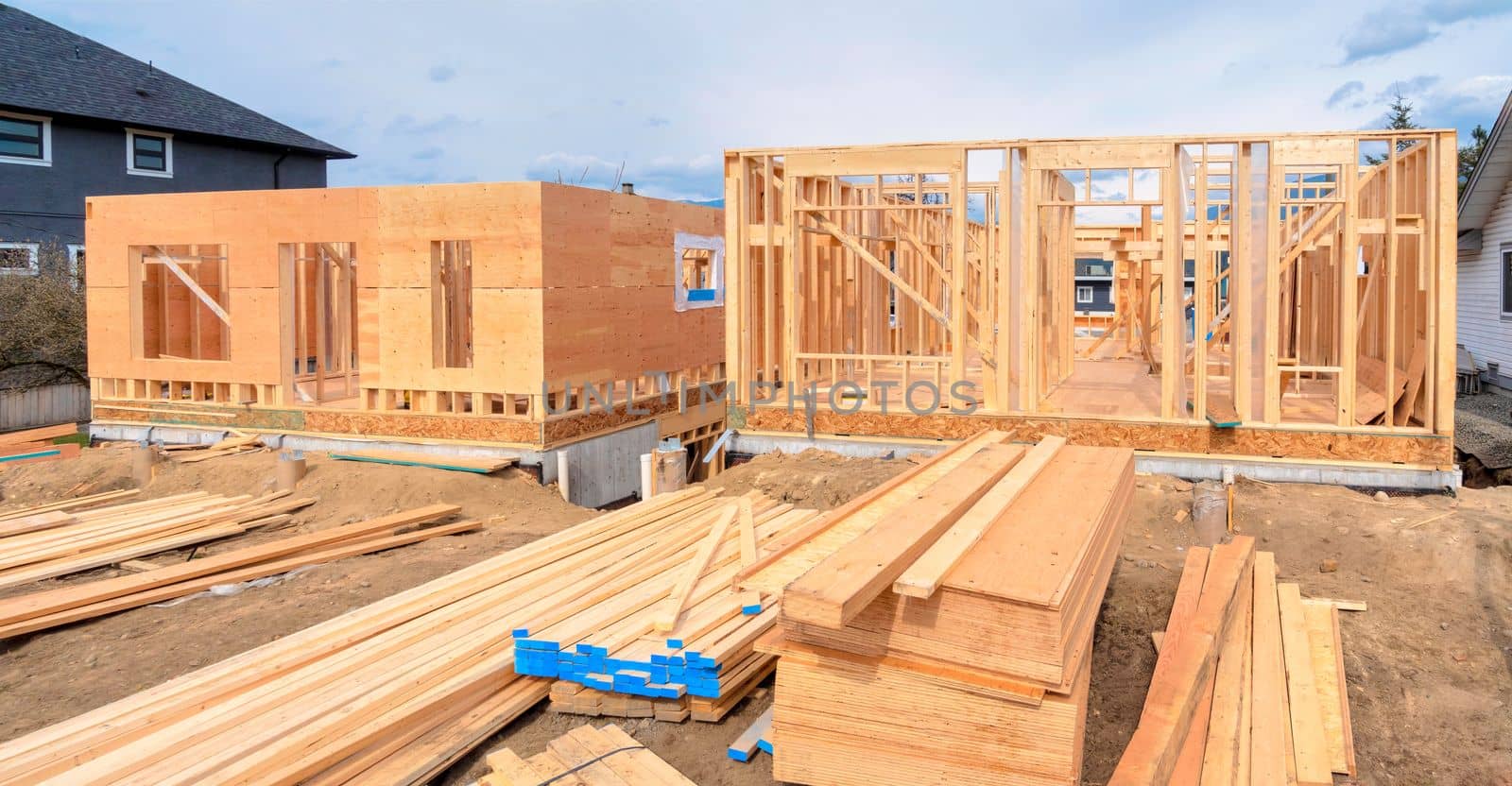 Wooden frame of two new houses with engineered lumber materials prepared for the construction. Panoramic view image