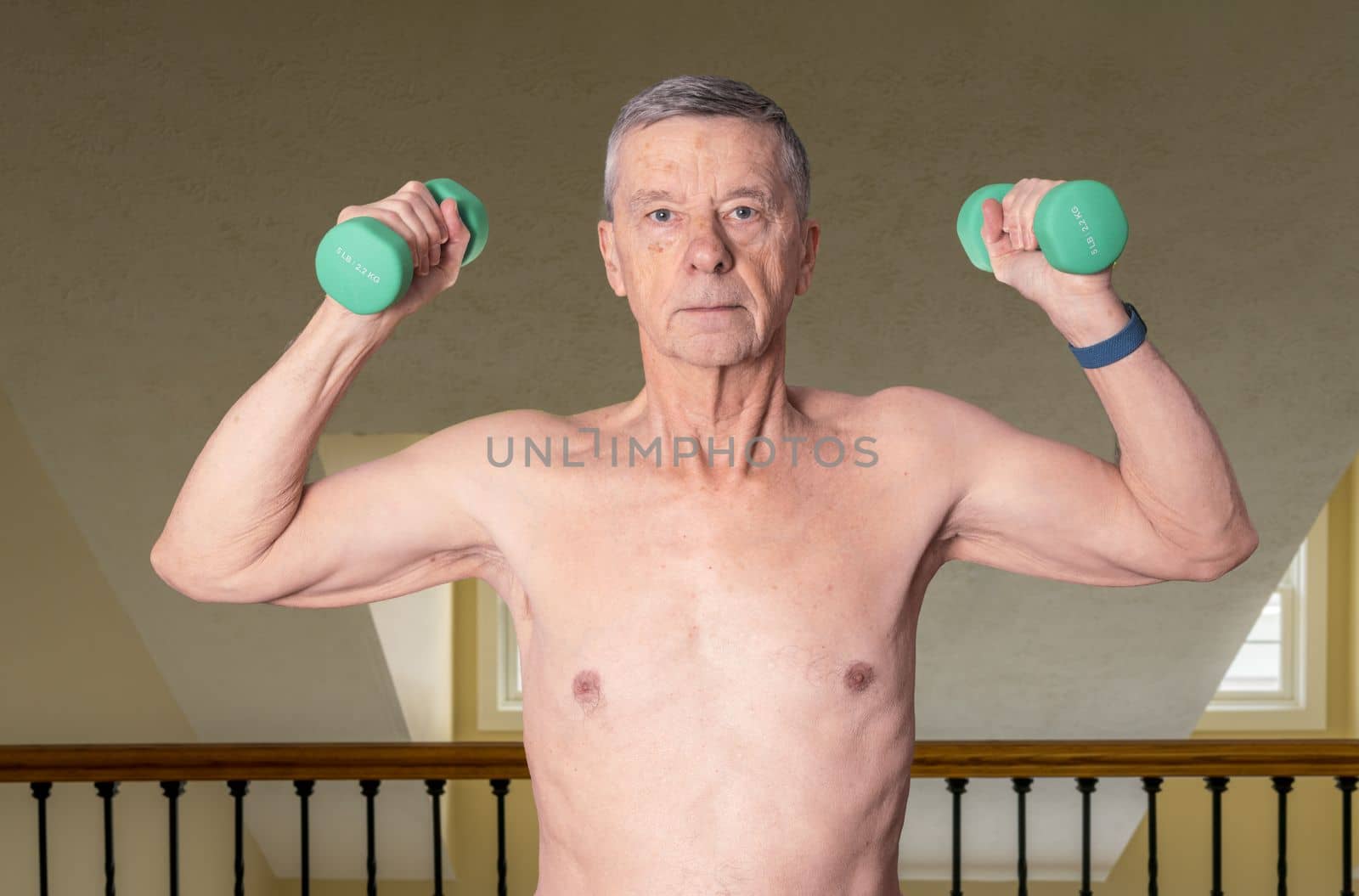 Senior man shirtless and exercising in bedroom with dumbbell by steheap
