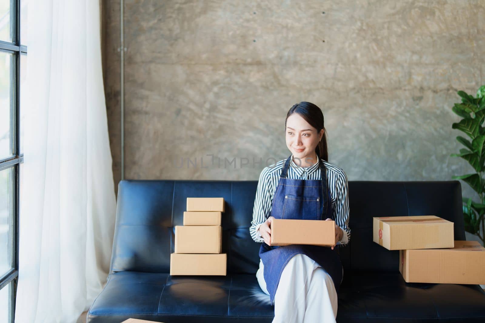 Starting small business entrepreneur of independent Asian female online seller packing products to send to customers and SME delivery concept by Manastrong