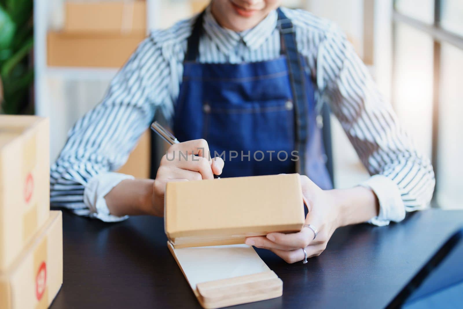 Starting small business entrepreneur of independent Asian female online seller packing products to send to customers and SME delivery concept by Manastrong