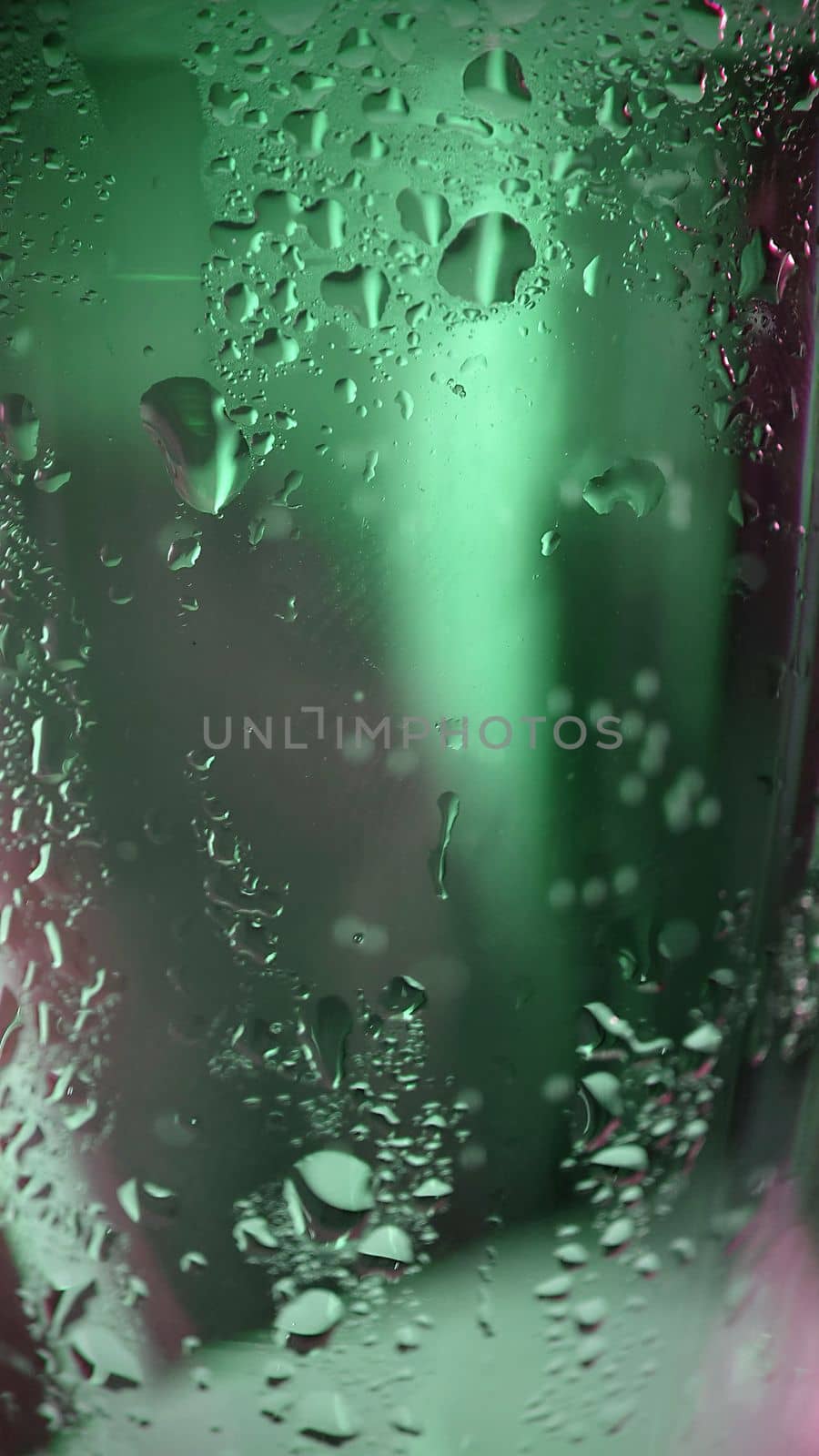Macro photography.Condensation drops on the glass surface of the glass with green illumination .Texture or background