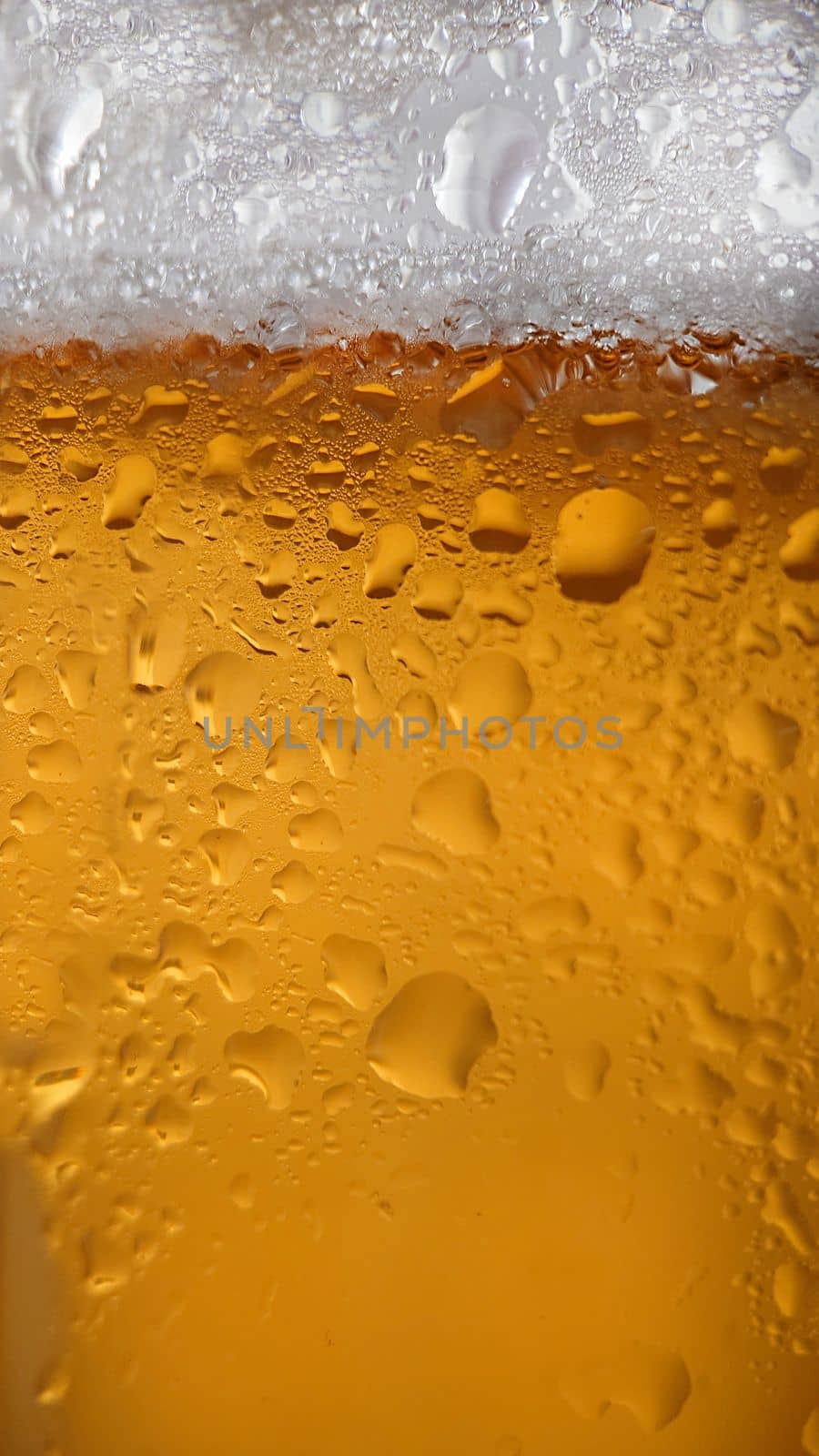 Macrophotography.Drops of condensation on a frothy beer chilled glass.Texture or background
