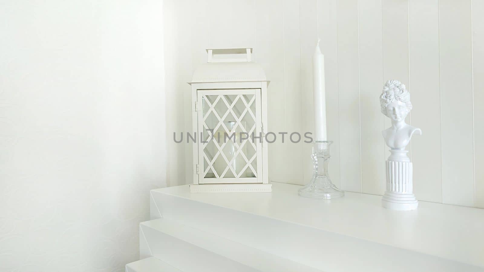 Texture or background. Home decor.A statuette of a woman, a lantern and a candlestick stand on a white fireplace