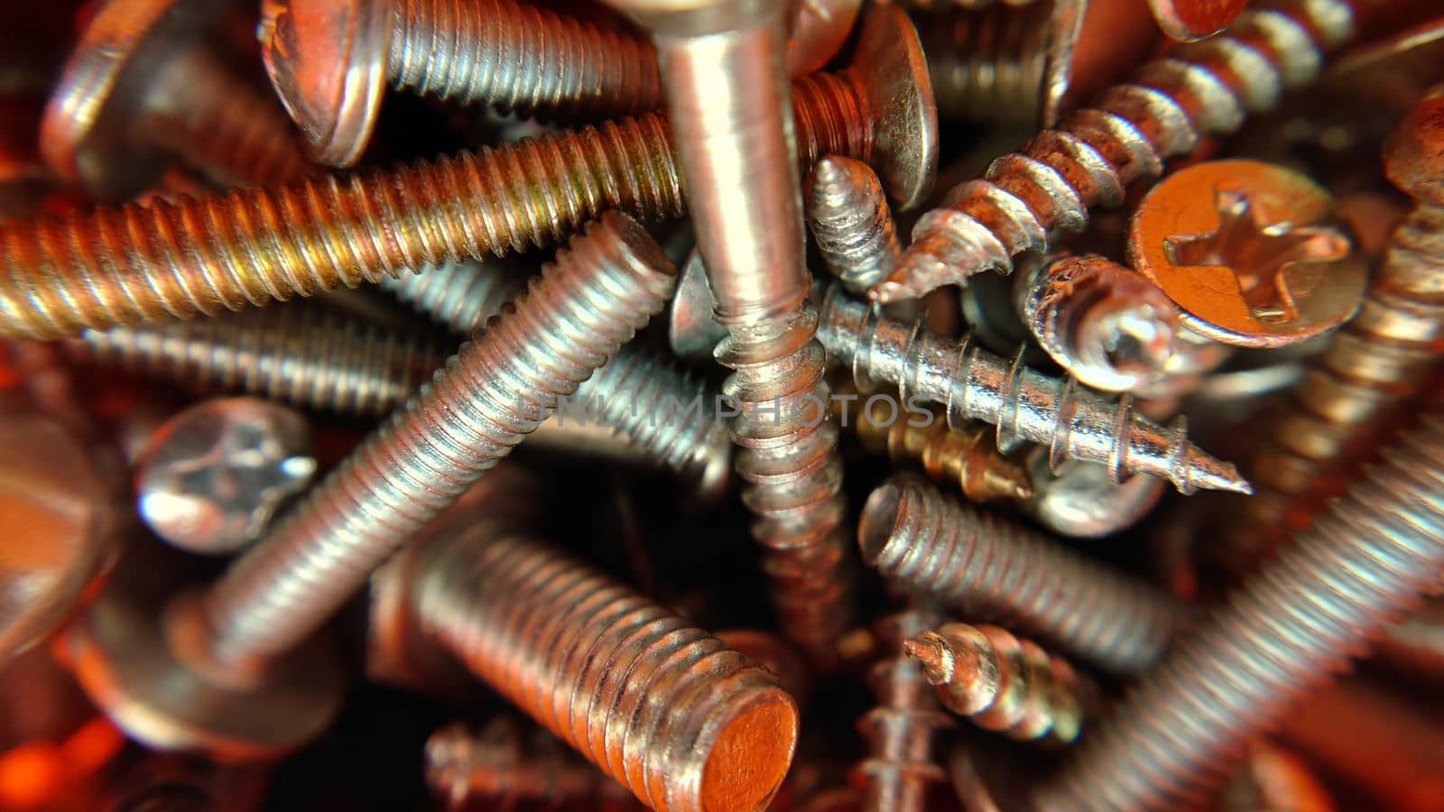 A bunch of randomly lying bolts screws nuts top view.Macrophotography.Texture or background.Selective focus.