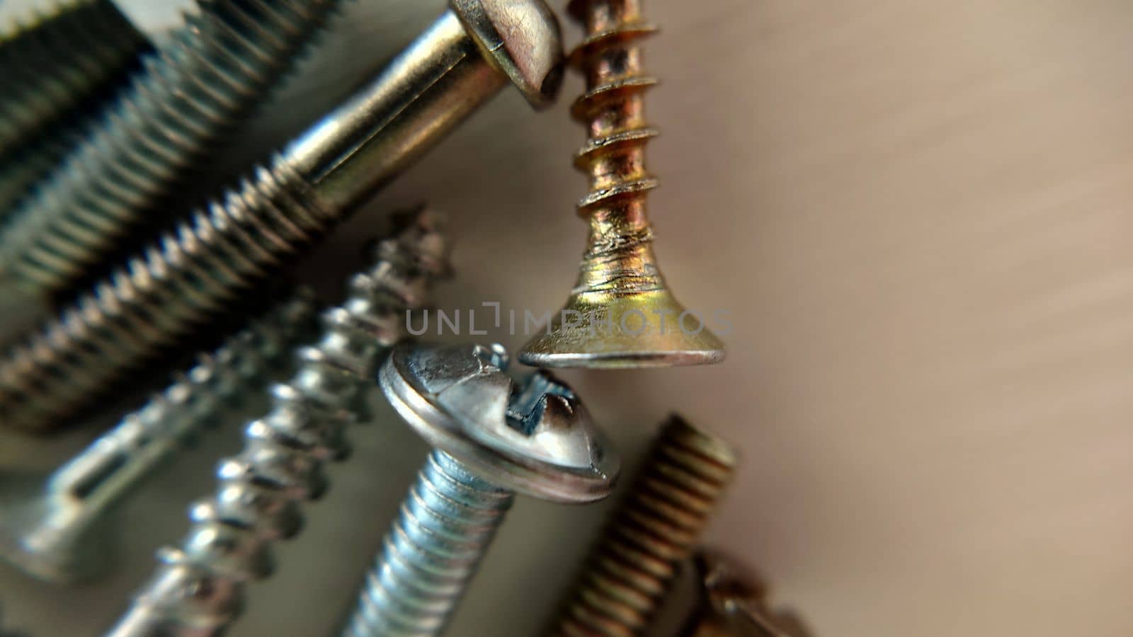 Screws bolts randomly lie close up on the table by Mastak80