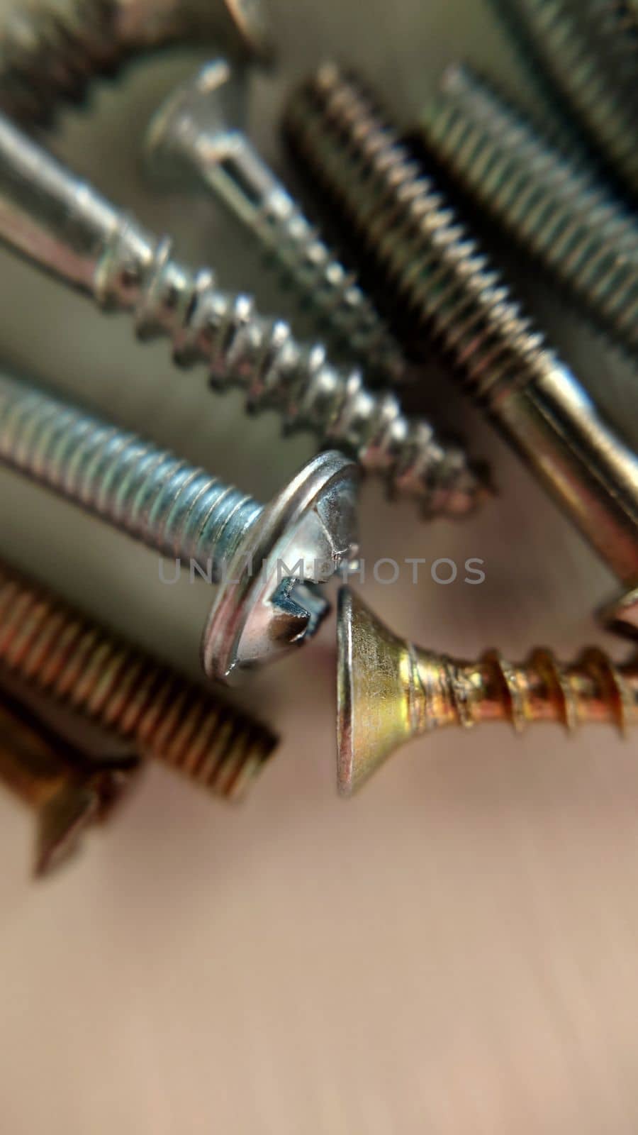 Screws bolts of different sizes and colors are mixed on the table. Macrophotography.Texture or background.Selective focus.