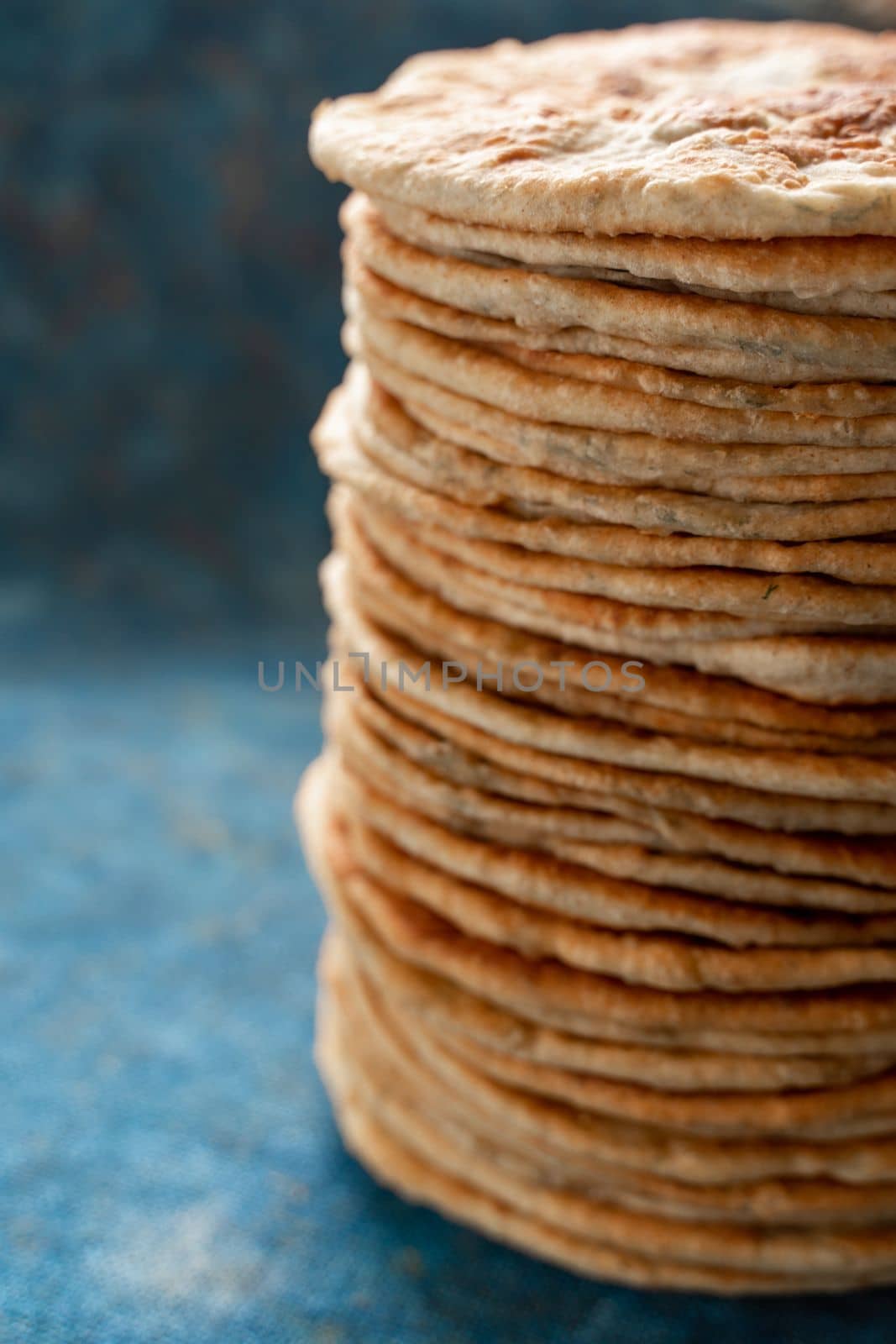 Flatbread lavash, chapati, naan, heap of tortilla on a blue background Homemade flatbread stacked. by Matiunina