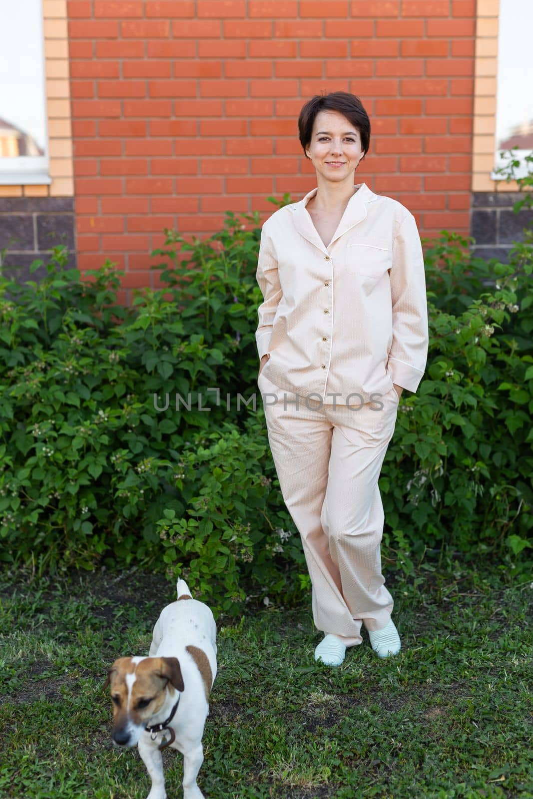 Young woman wearing pajama with her dog on backyard. The concept of animals and friendship or pet owner and love by Satura86