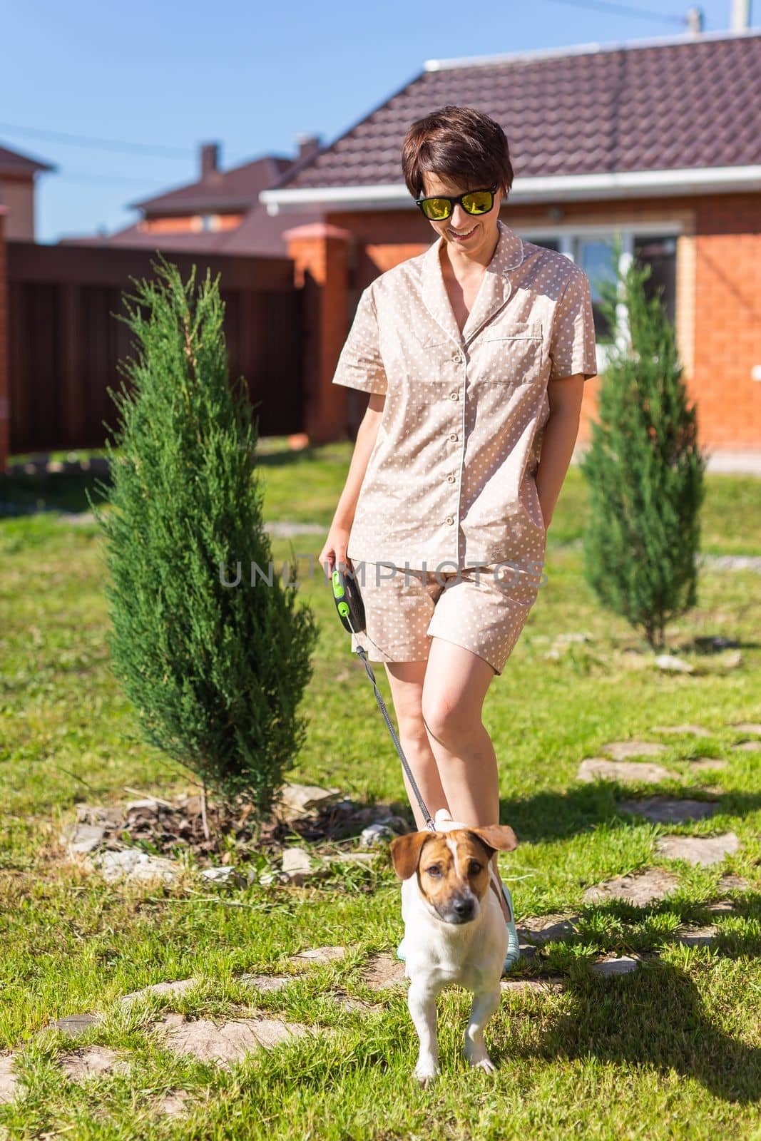 Young woman wearing pajama with her dog on backyard. The concept of animals and friendship or pet owner and love by Satura86