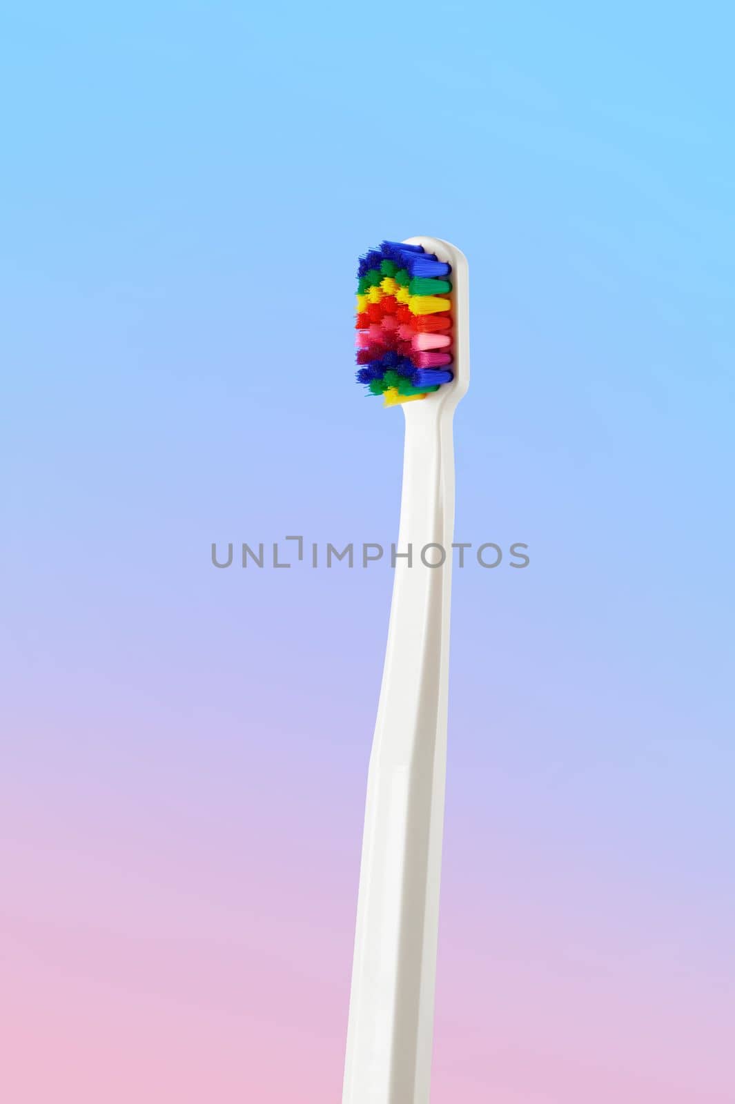 White toothbrush with multicolored bristles. Bristles in all colors of the rainbow. Rainbow toothbrush with white knob. Fashionable oral care