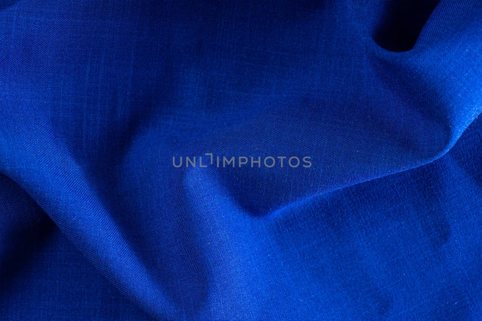 Texture of fabric for furniture upholstery. Wear and water resistant fabric in deep folds top view. Blue fabric texture closeup top view. by SERSOL