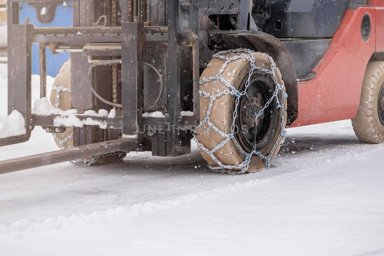 Tractor wheel with chain. Tractor or loader on a slippery snowy road. Loaders drive on snow with anti-skid chains