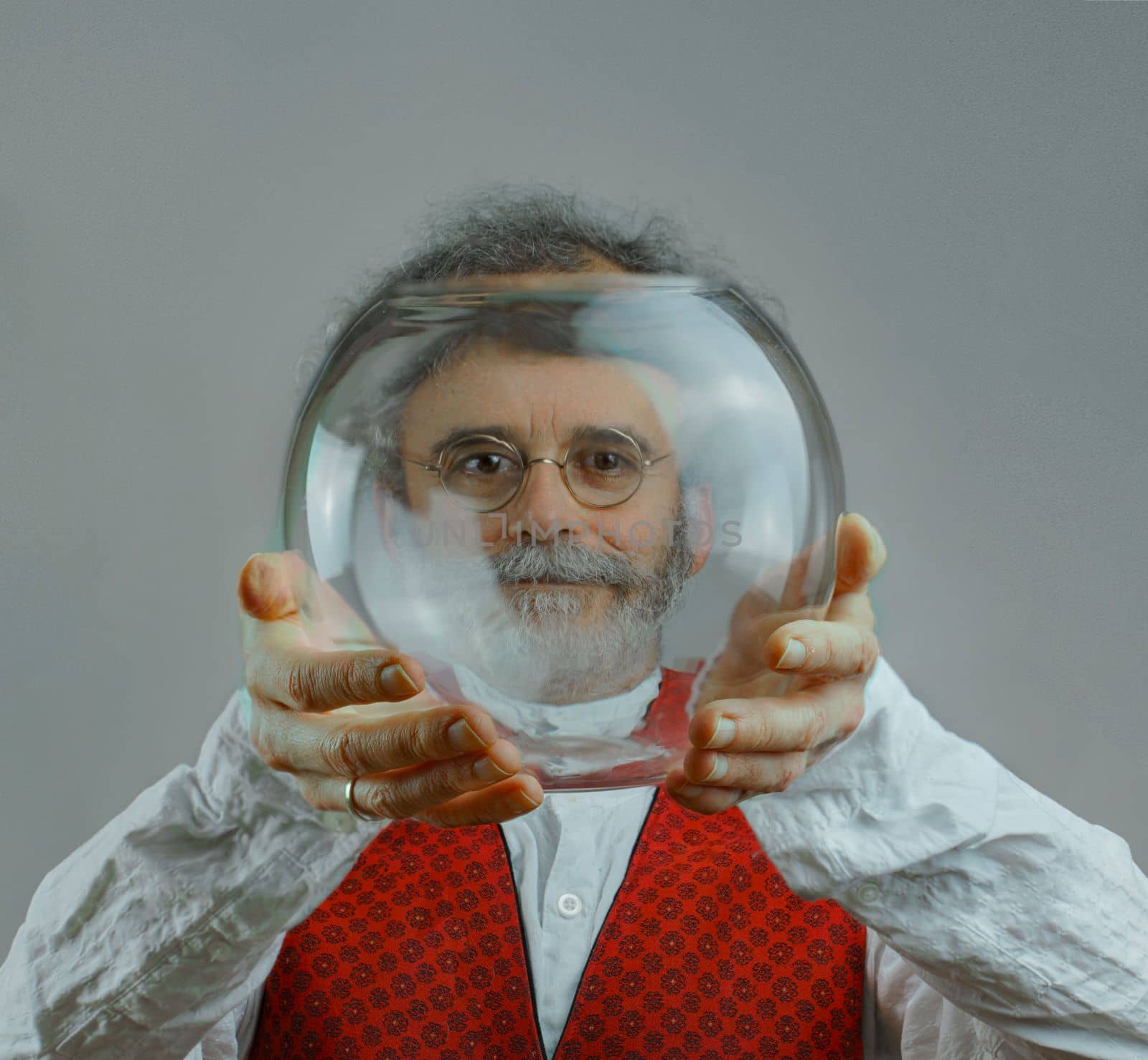 a colorful man with curls, a beard and a silver-colored mustache holds a transparent glass ball in his hands and looks through this ball by Costin