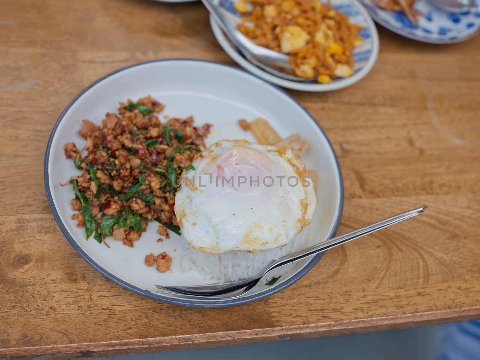 Pad Krapow MOO - Thai Basil Pork with Rice and fried Egg  background. Thai cuisine dish with minced  pork , basil, soy and oyster sauces. Thai Food Copy space by Hepjam