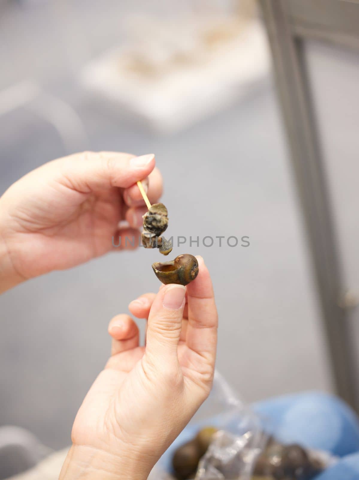 Woman hand on Thai-style boiled snails with Spicy seafood sauce , popular street food by Hepjam