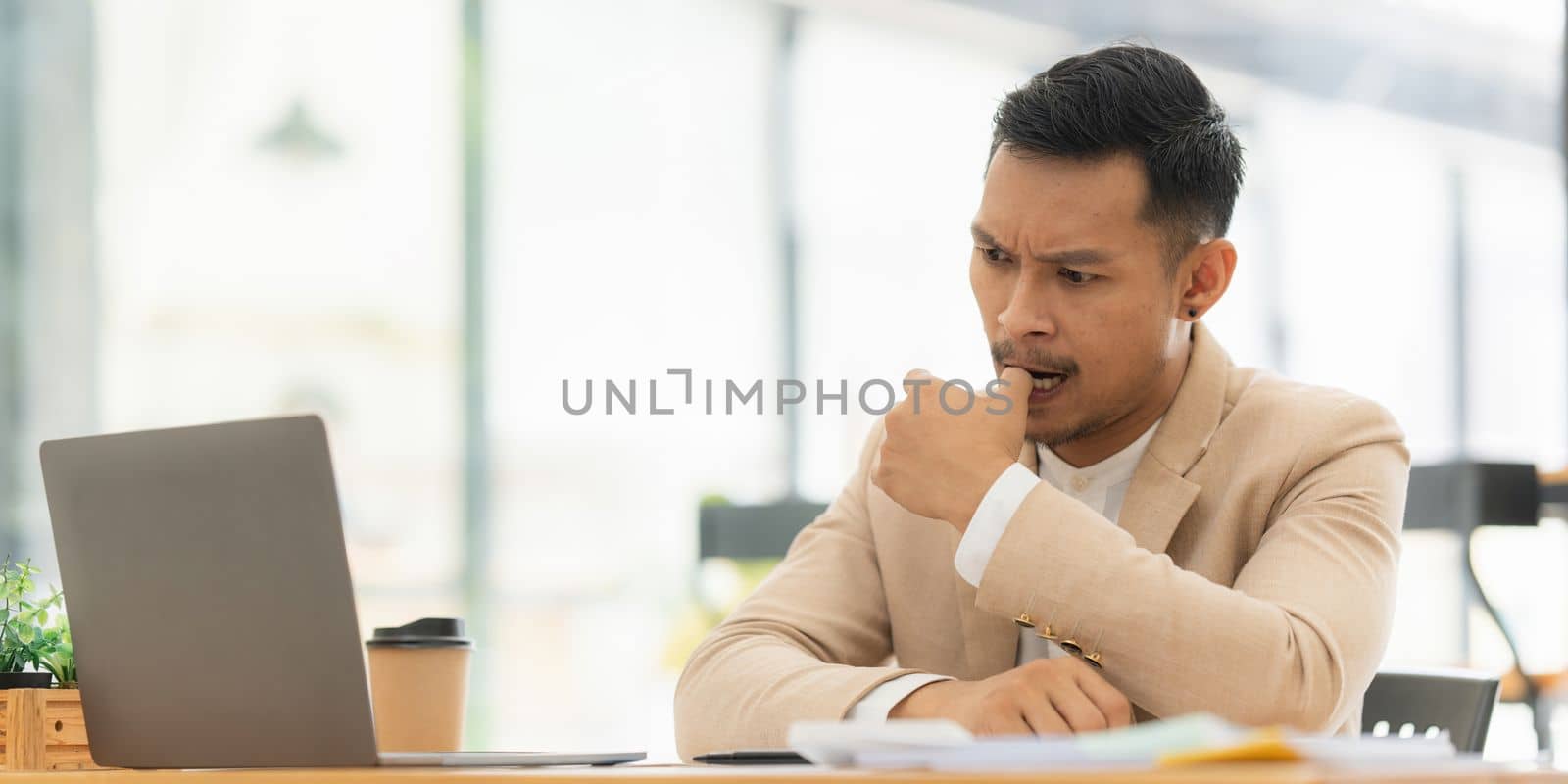 Stressed Asian businessman worry with many document on desk at office.