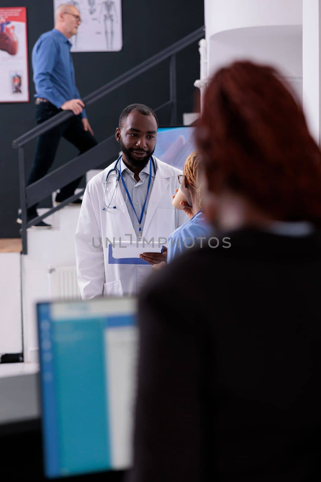 Practitioner doctor talking with nurse discussing patient symptoms while planning health care treatment to help cure disease. Medical staff working in hospital waiting area during consultation