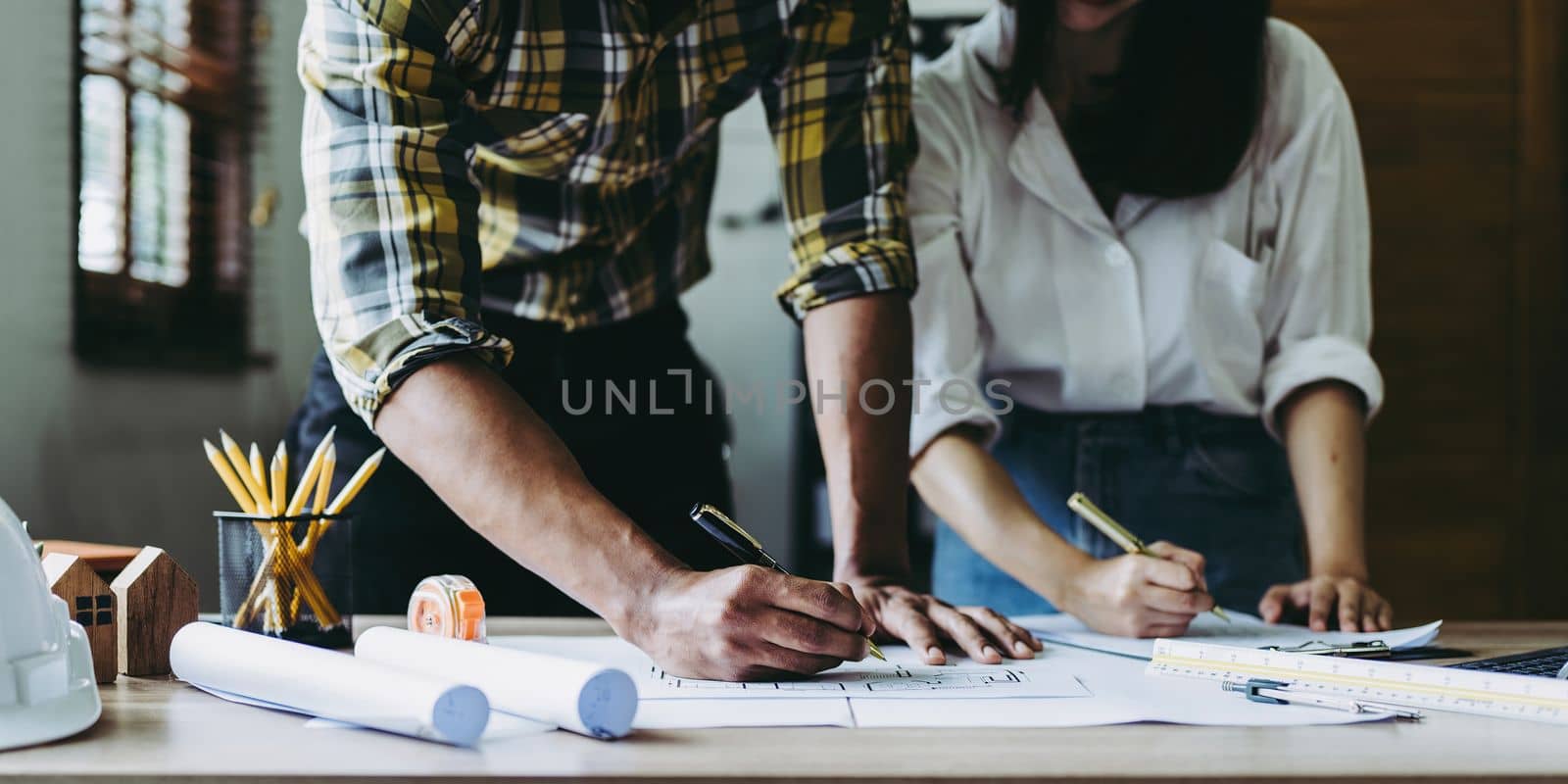 Architect man working with blueprints for architectural plan, engineer sketching a construction project concept by itchaznong