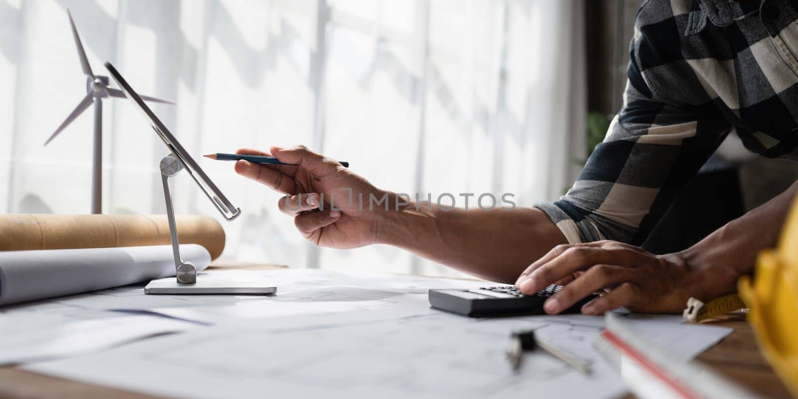 Architect man working with blueprints for architectural plan, engineer sketching a construction project, green energy concept.