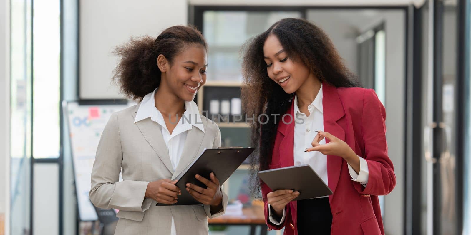 Smiling young African American businesswoman working with partner at office. finance concept by itchaznong