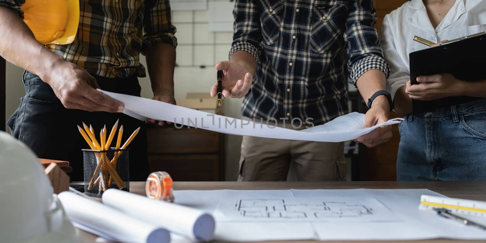 Architect man working with blueprints for architectural plan, engineer sketching a construction project concept.