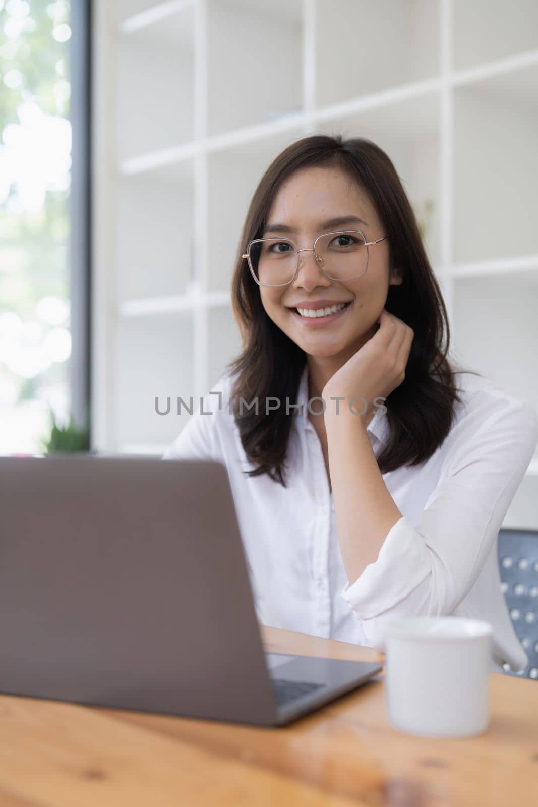 Asian entrepreneur making business plan while working on laptop with empty screen.