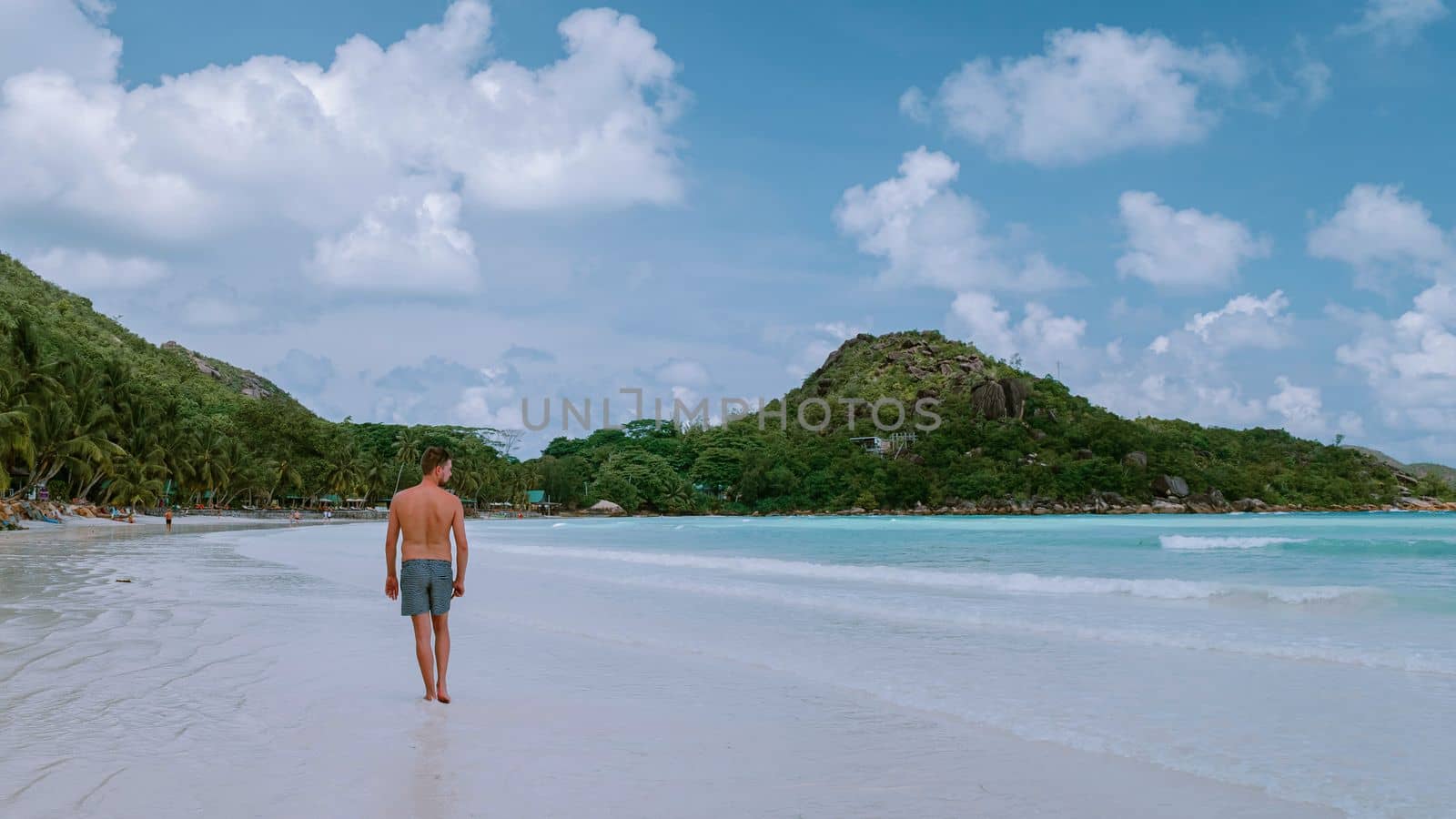 Cote d'Or Beach Praslin Seychelles, young mid age men in swim short walking on the beach during vacation Seychelles tropical Island, white guy on the beach during holiday Praslin Seychelles