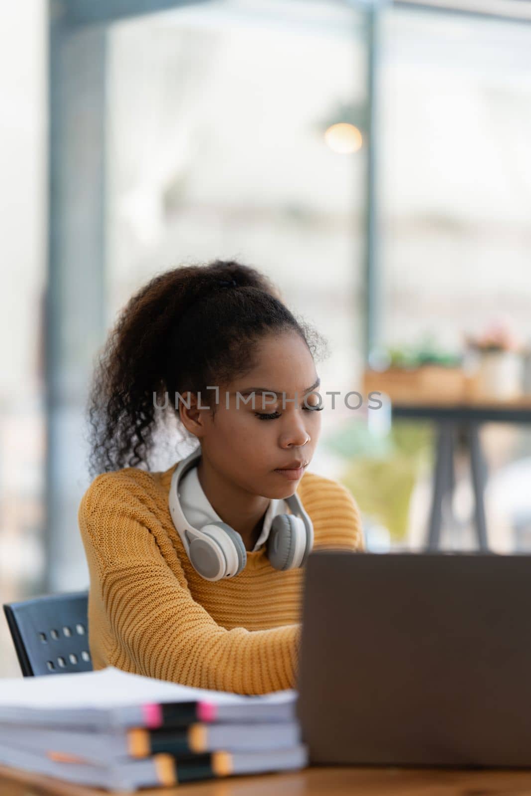 Portrait of beautiful young black woman using laptop at cafe.