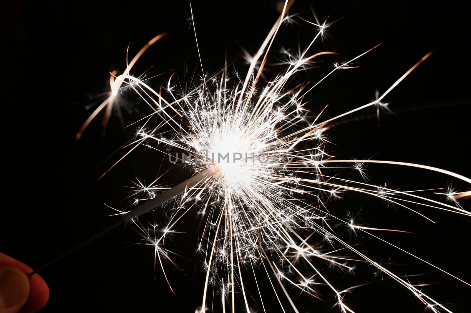 Christmas background. A sparkler on a Christmas tree in the evening outside with snow. Concept for winter season, holidays and new year 2023. by Montypeter