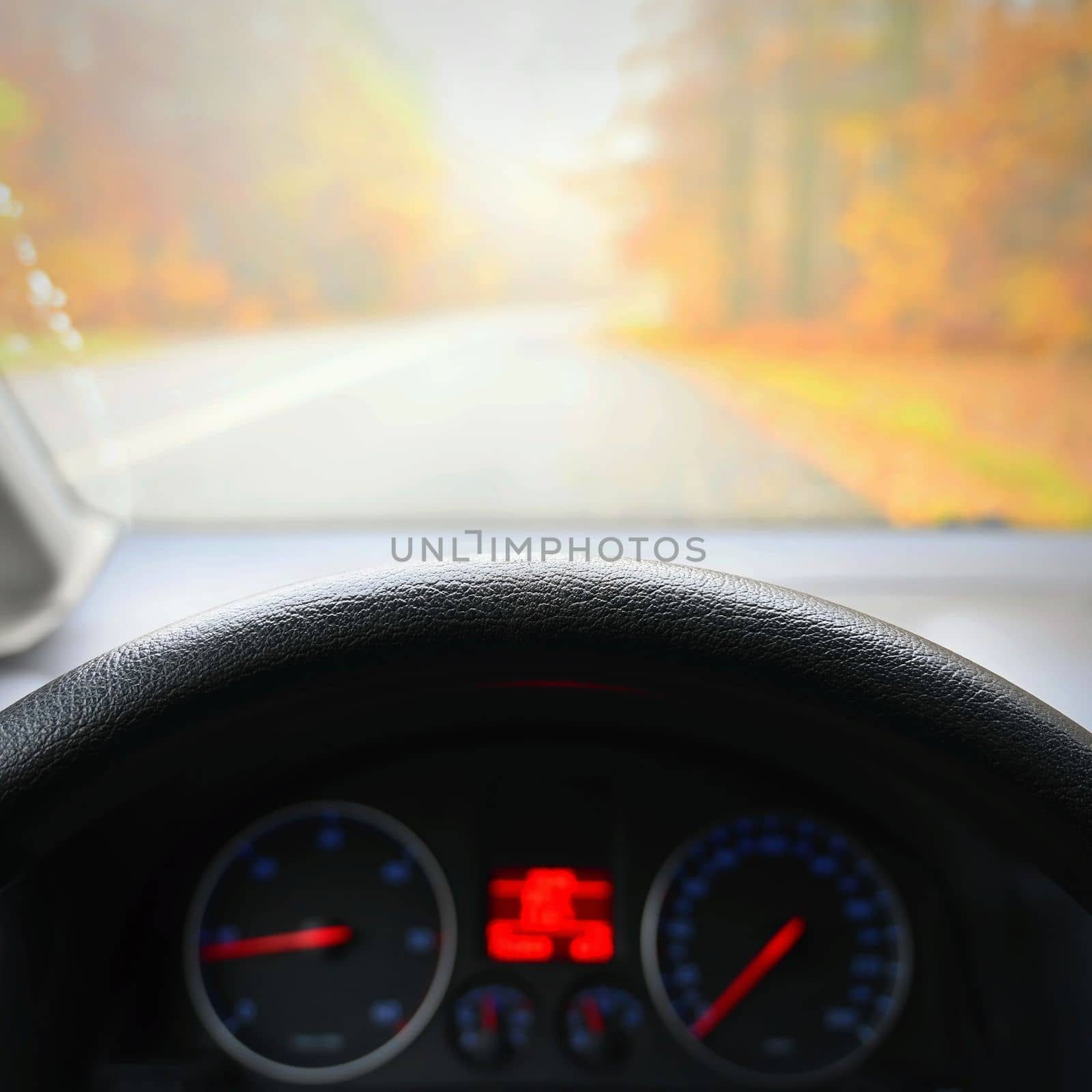 Car interior with dashboard on wet road in autumn season. Foggy and dangerous driving - concept for traffic and road safety - view from the driver's seat.