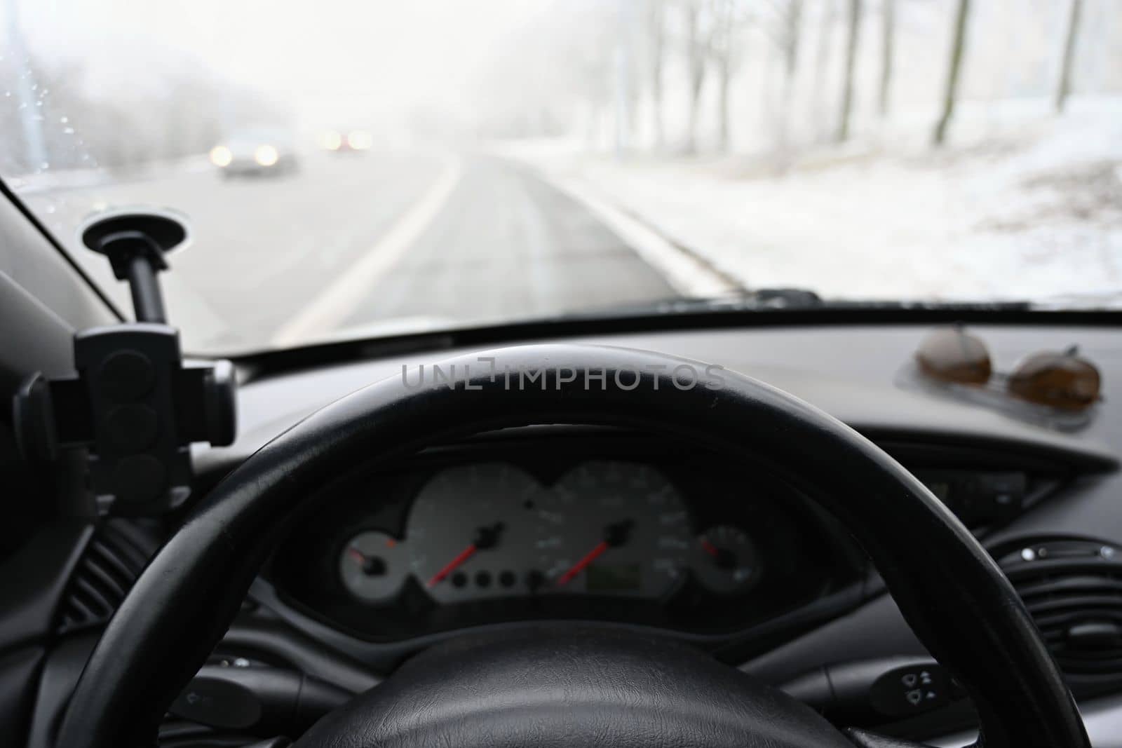 Dangerous winter season with snow on the road. The interior of the car from the driver's point of view - dangerous traffic in bad weather. by Montypeter