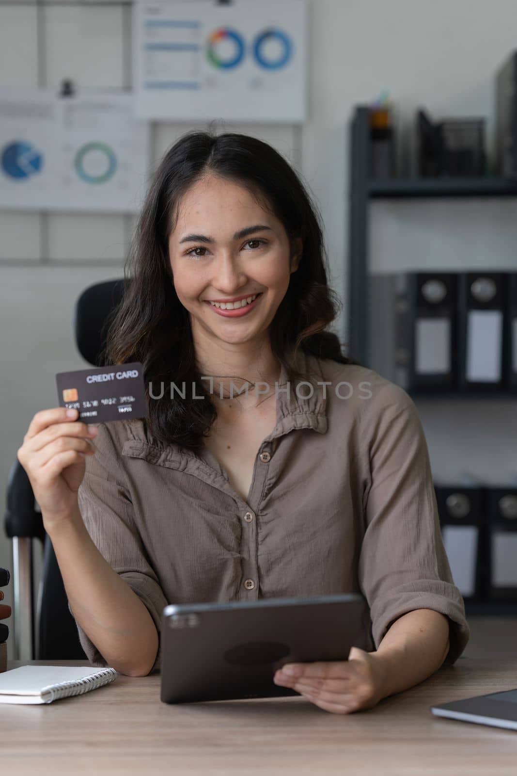 Young woman holding credit card. Businesswoman working at home. Online shopping, e-commerce, internet banking, spending money, working from home concept.