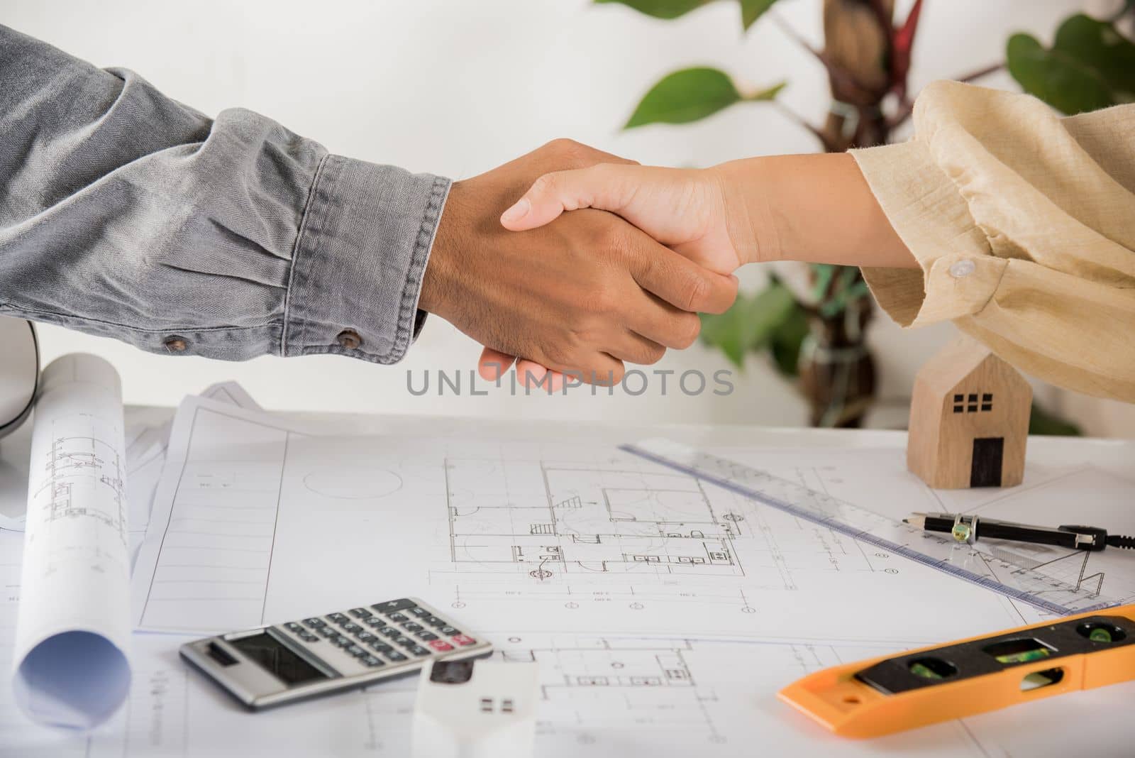 Architect team success and handshaking after meeting consult and work for architectural construction project with partner editing on blueprint paper plans, Architect and engineer shaking hands