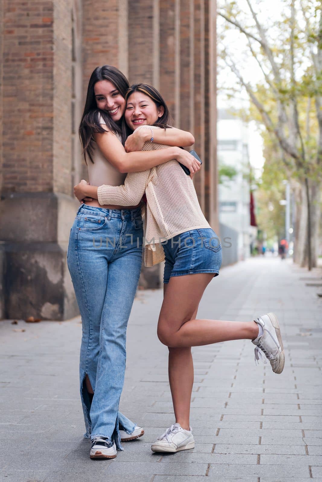 two young women smiling and hugging looking at camera, concept of friendship and love between people of the same sex