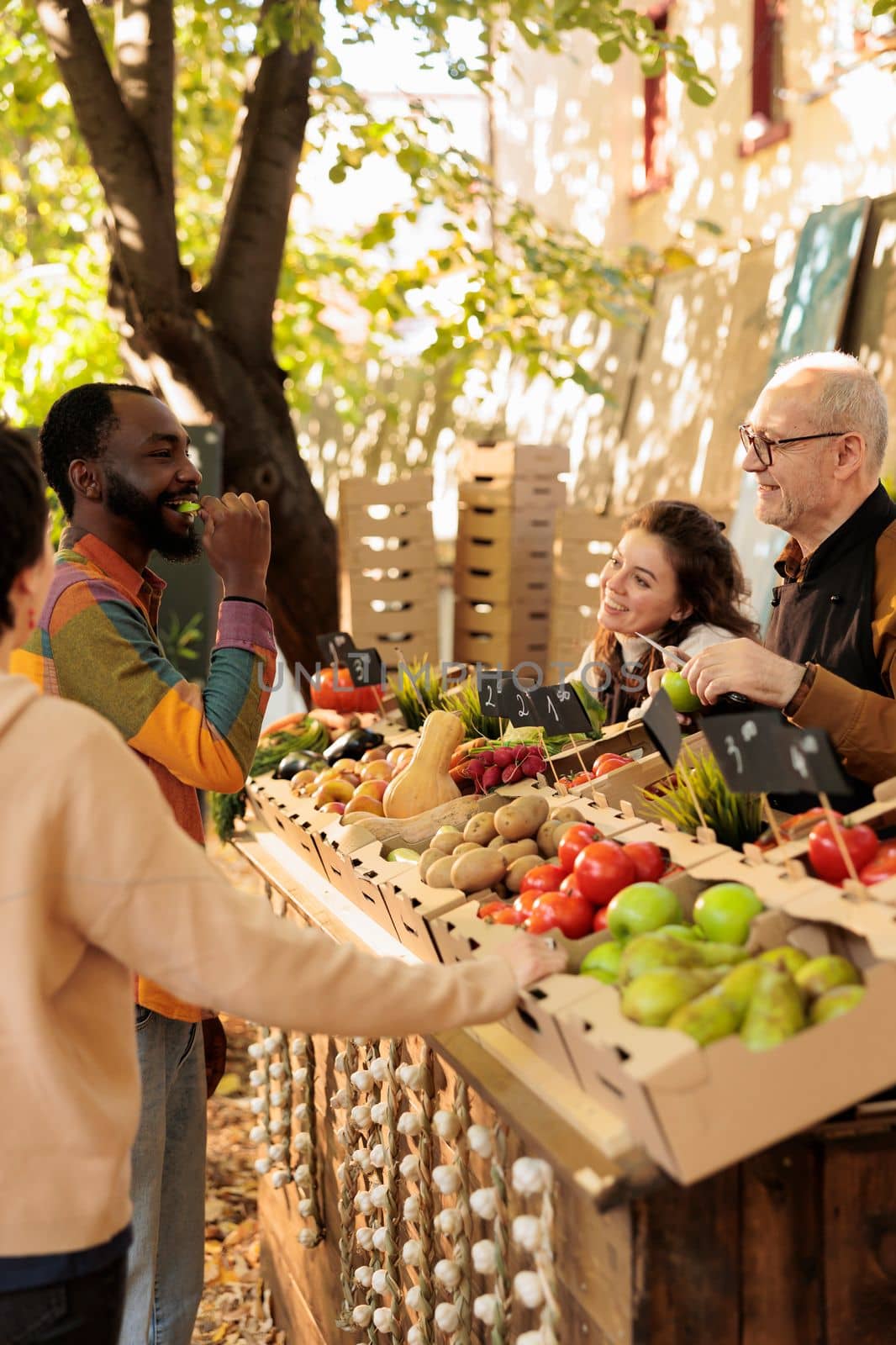 African guy tasting fresh organic produce at farmers market by DCStudio