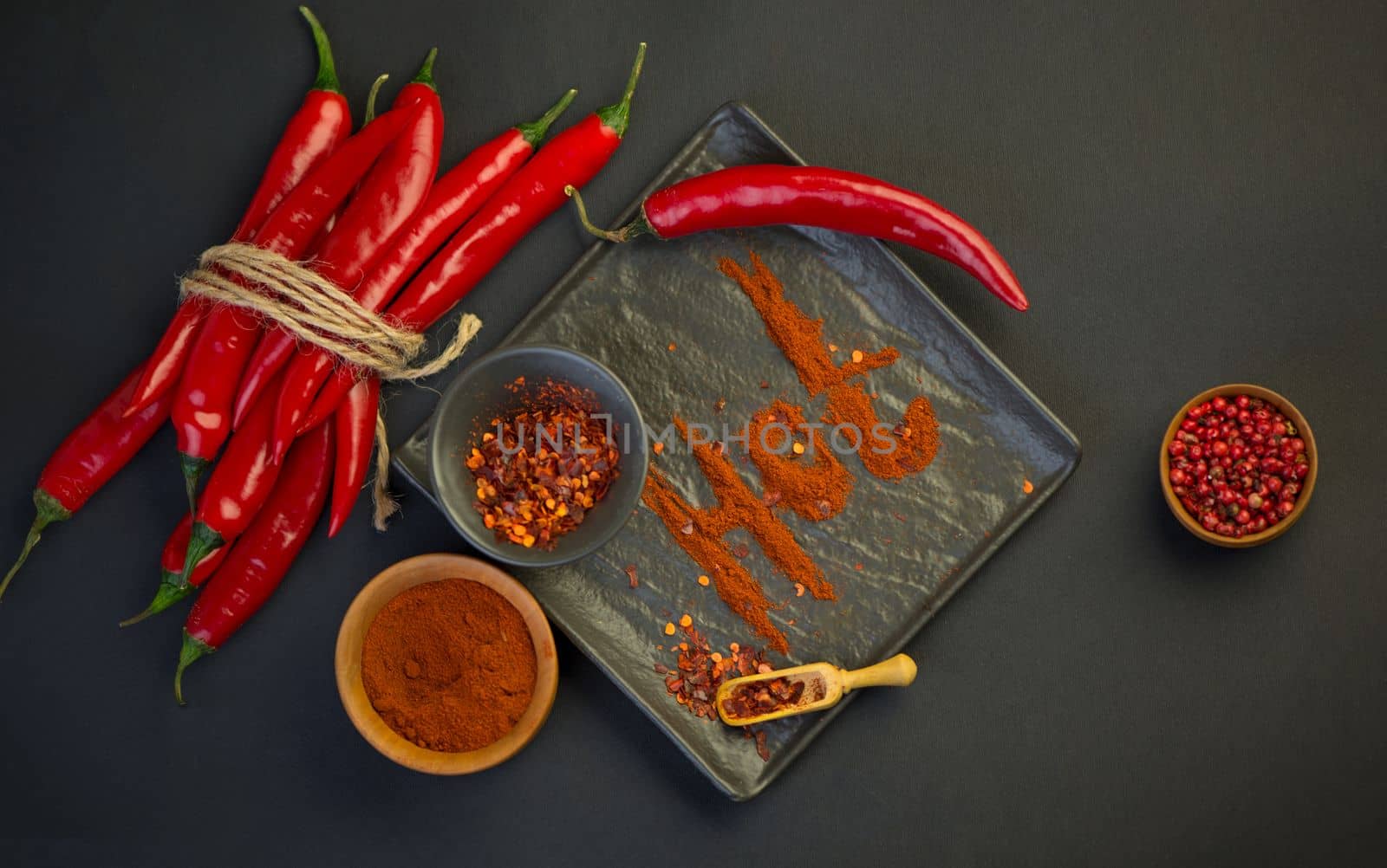 Chili pepper isolated on a black background. Knitted hot chili pepper tied with a rope. Red chili pepper cut into pieces on a black background. by aprilphoto