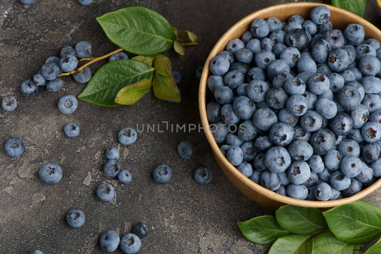 Fresh blueberries with water drops in a wooden bowl. View from above. The concept of healthy and diet food by aprilphoto